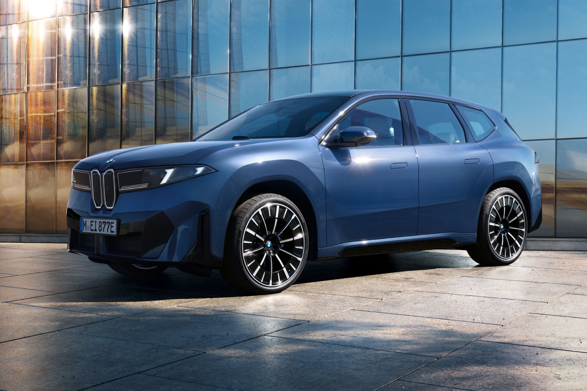 BMW iX3 steht parkend vor einem Gebäude mit Glasfassade