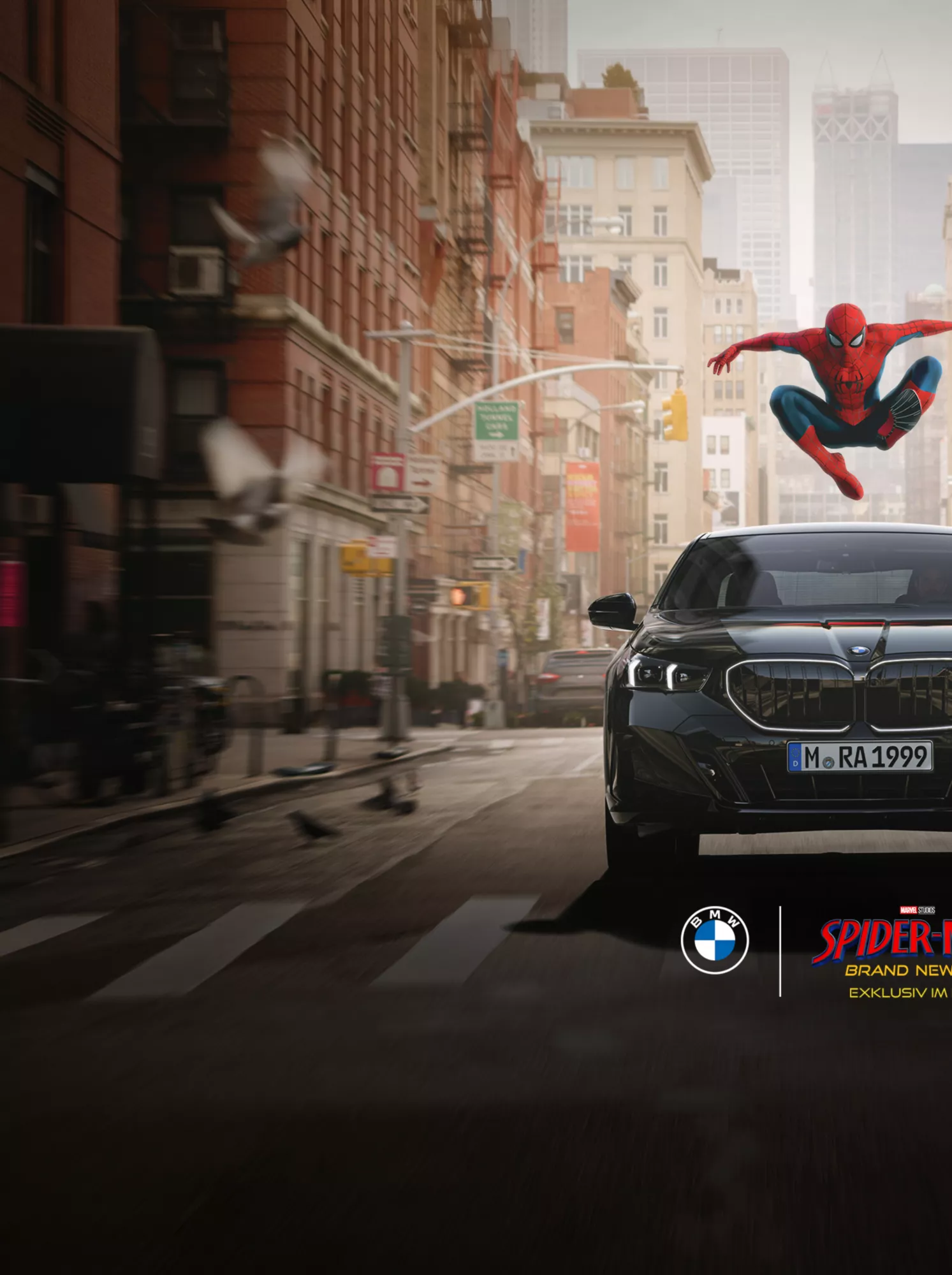 Eine schwarze BMW i5 Limousine fährt auf einer Stadtstraße zwischen hohen Gebäuden. Über dem Fahrzeug springt Spider-Man. Im unteren Bereich befinden sich die BMW- und Spider-Man-Logos.