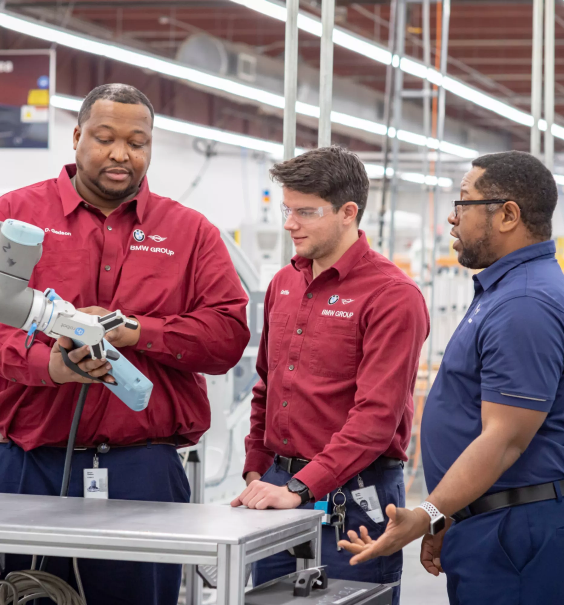 A BMW Group employee instructs two colleagues inside a factory