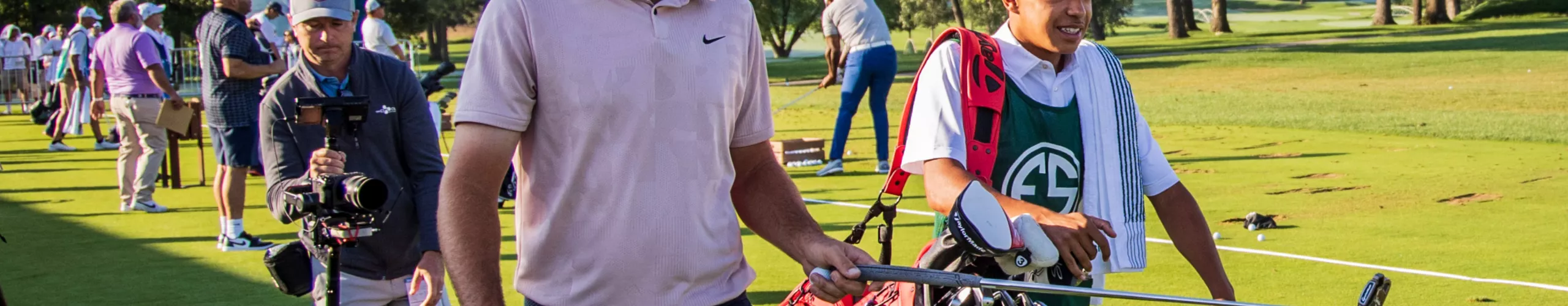 A professional golfer crouches as he analyzes a putt at the BMW Championship