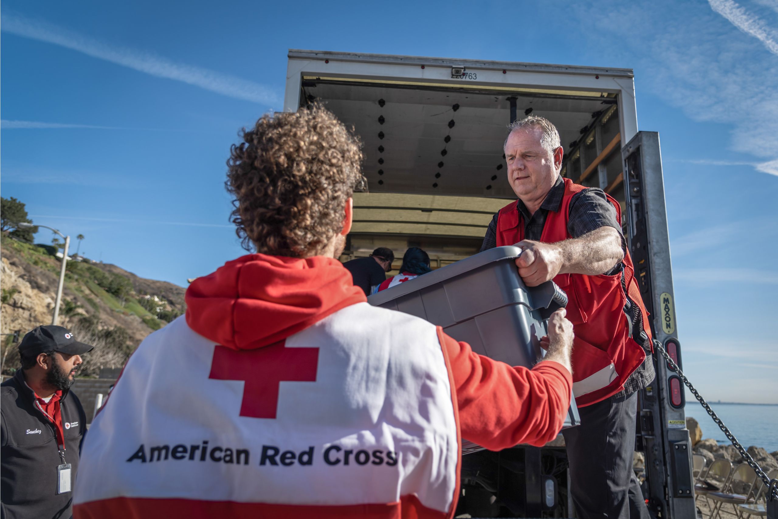 Two Red Cross workers unloading boxes from a truck