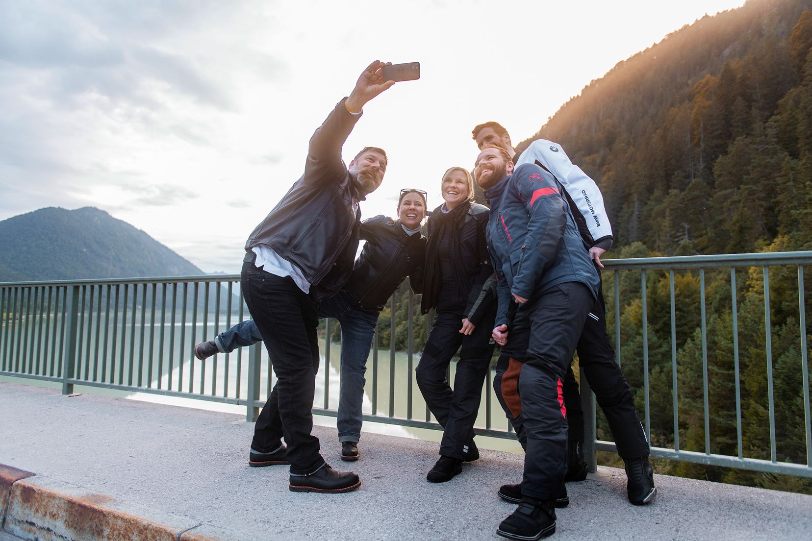 Four people wearing Motorrad apparel taking a selfie in front of a scenic landcape