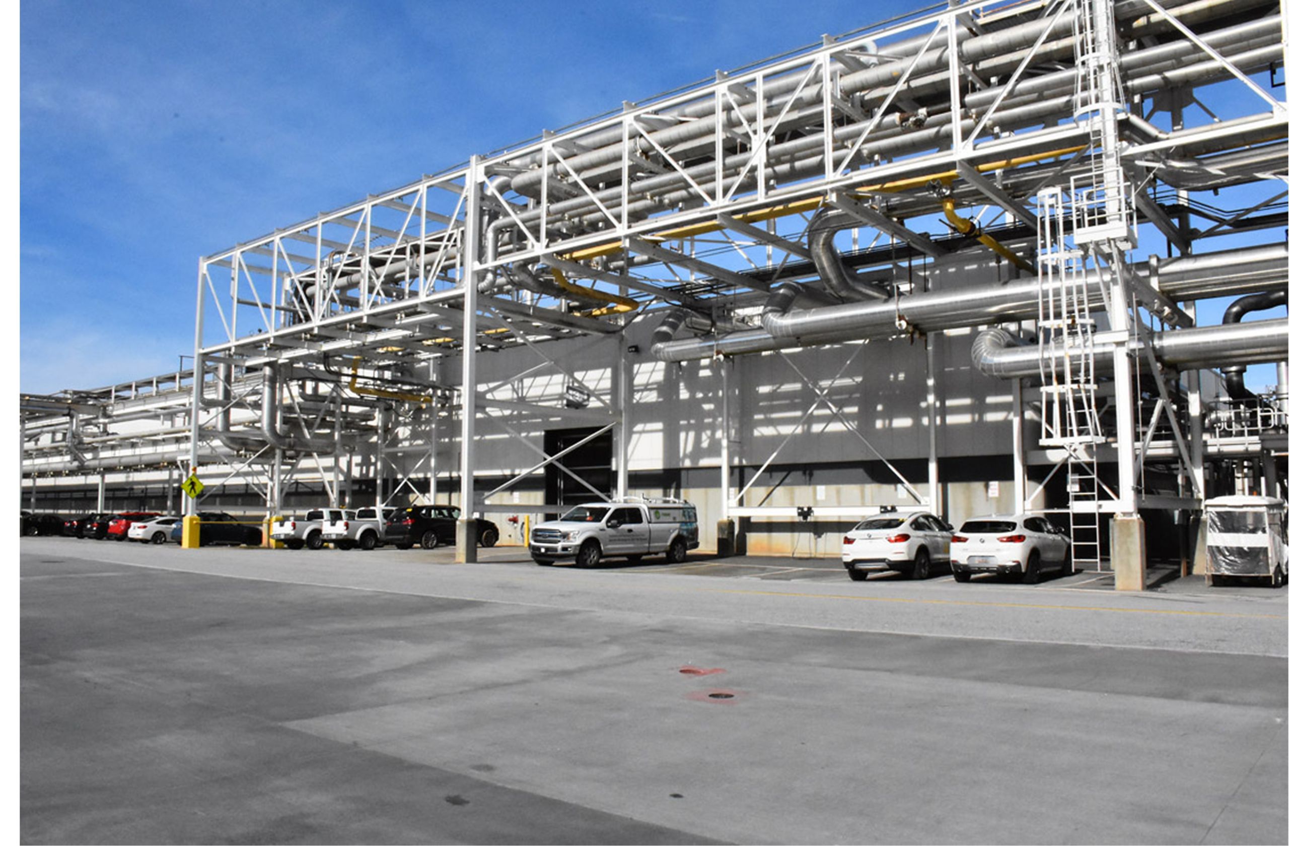 An exterior shot of a BMW factory with several BMW vehicles parked in front