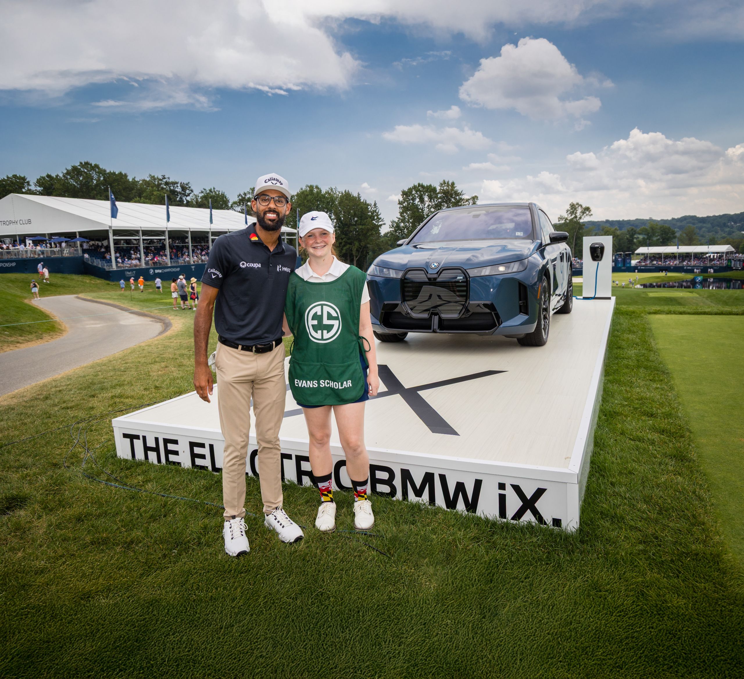 Golfer Akshay Bhatia poses with an Evans Scholar in front of a BMW iX at the BMW Championship.