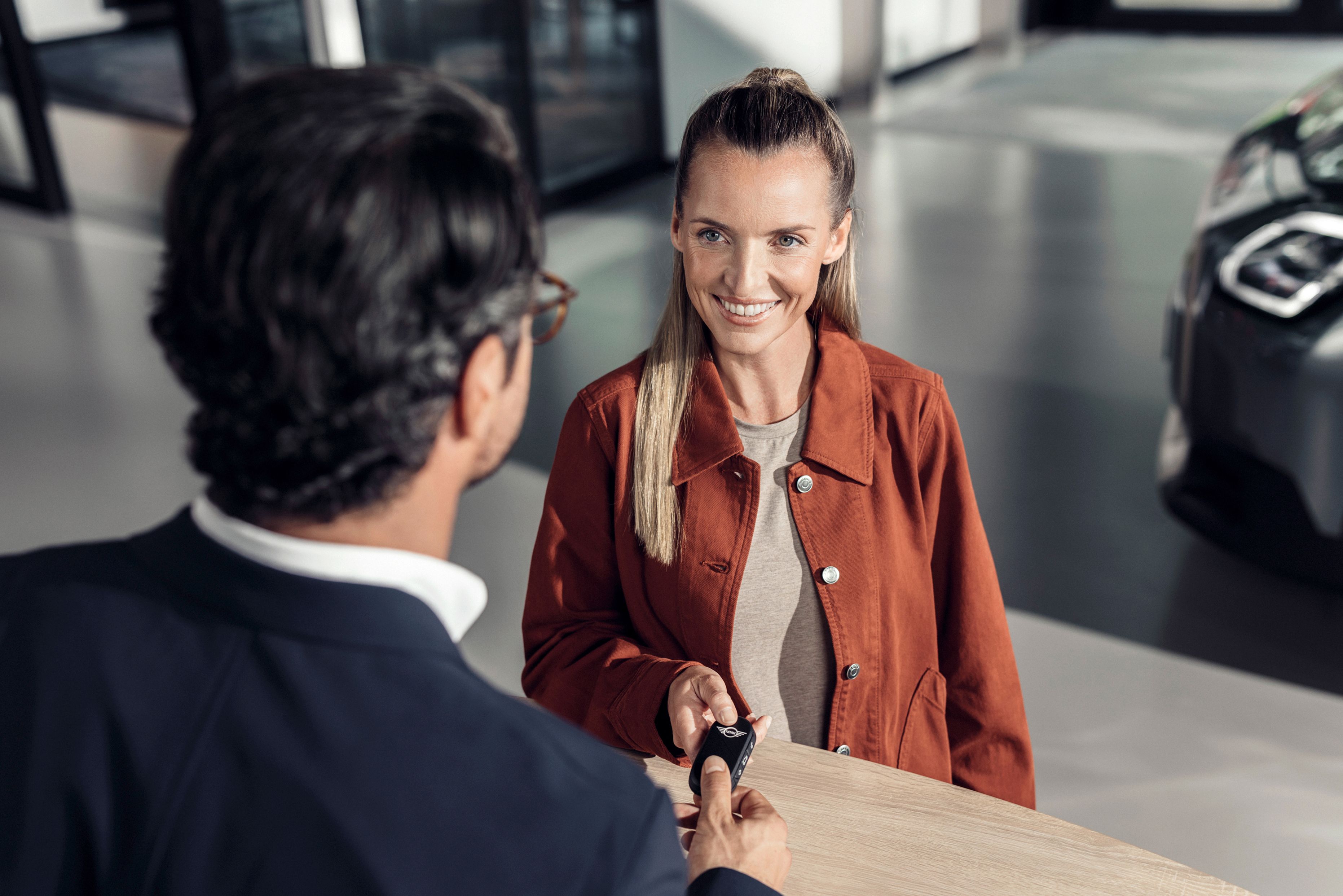 A woman receiving a set of keys from a BMW representative