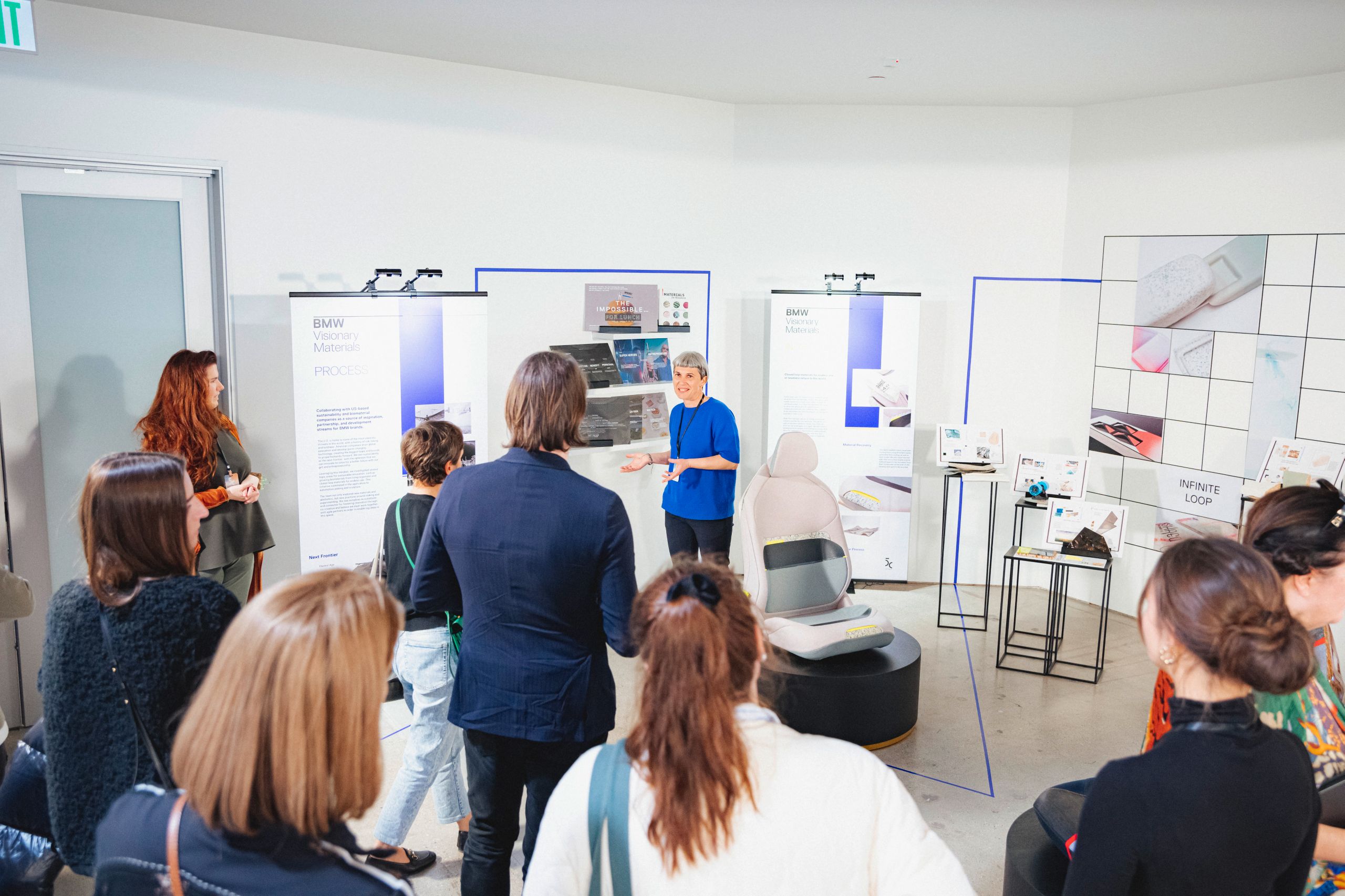 A woman gives a presentation in front of several large boards displaying content about sustainable materials
