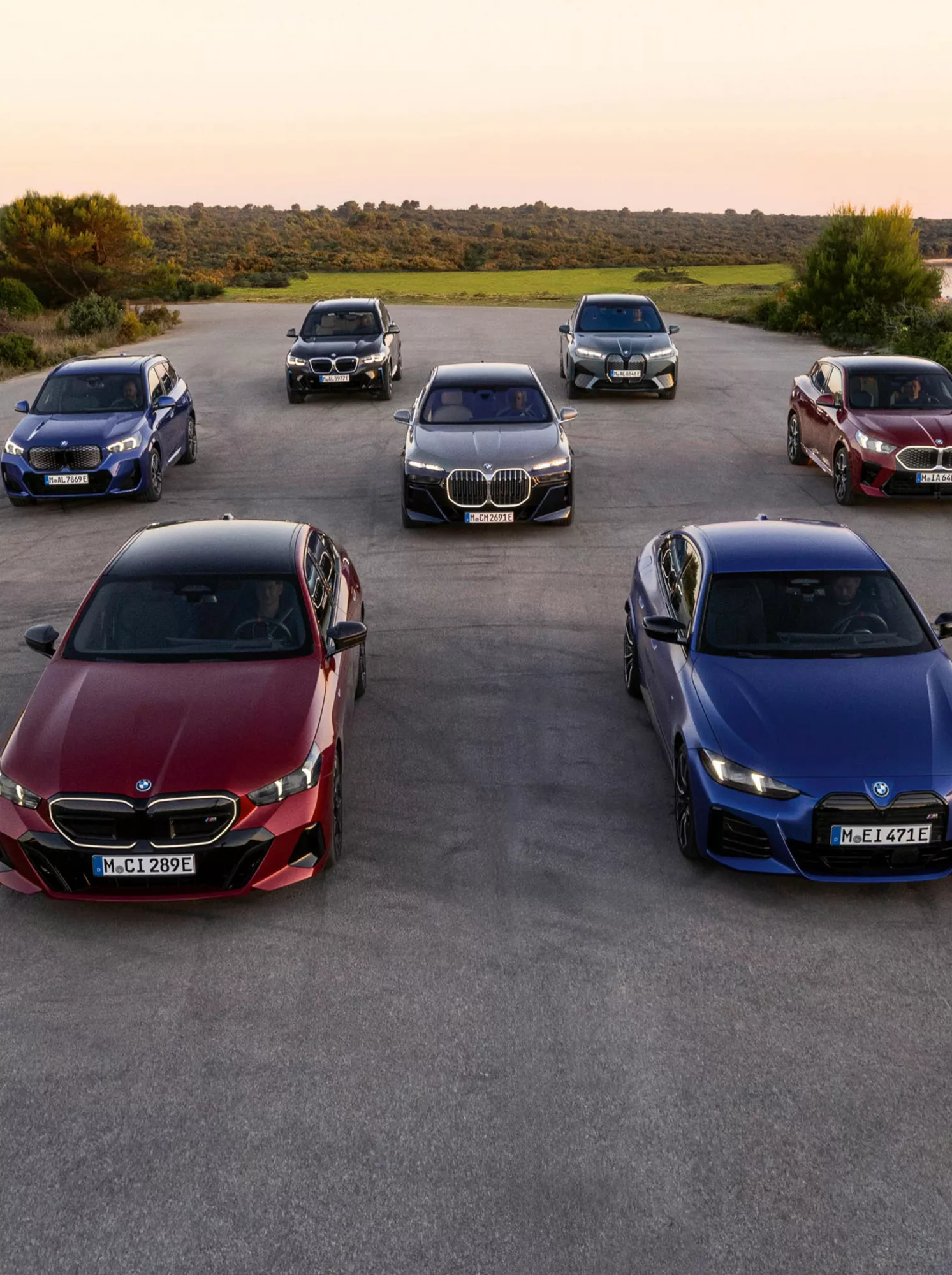 BMW elbilar uppradade på en parkering med natur i bakgrunden.