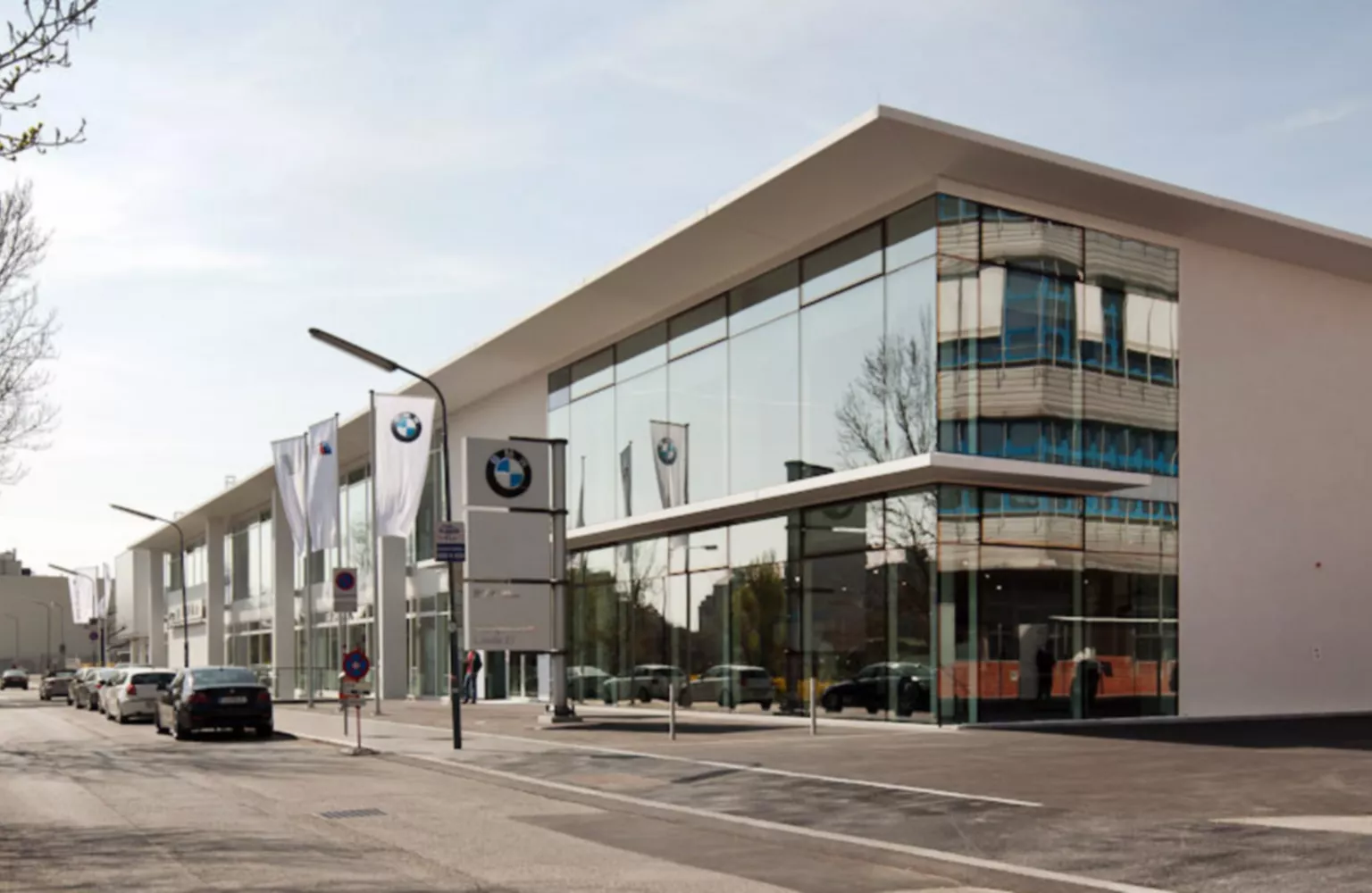 Seitenansicht der BMW Group Niederlassung Wien, bei der die große Fensterfront im Mittelpunkt des Bildes steht.