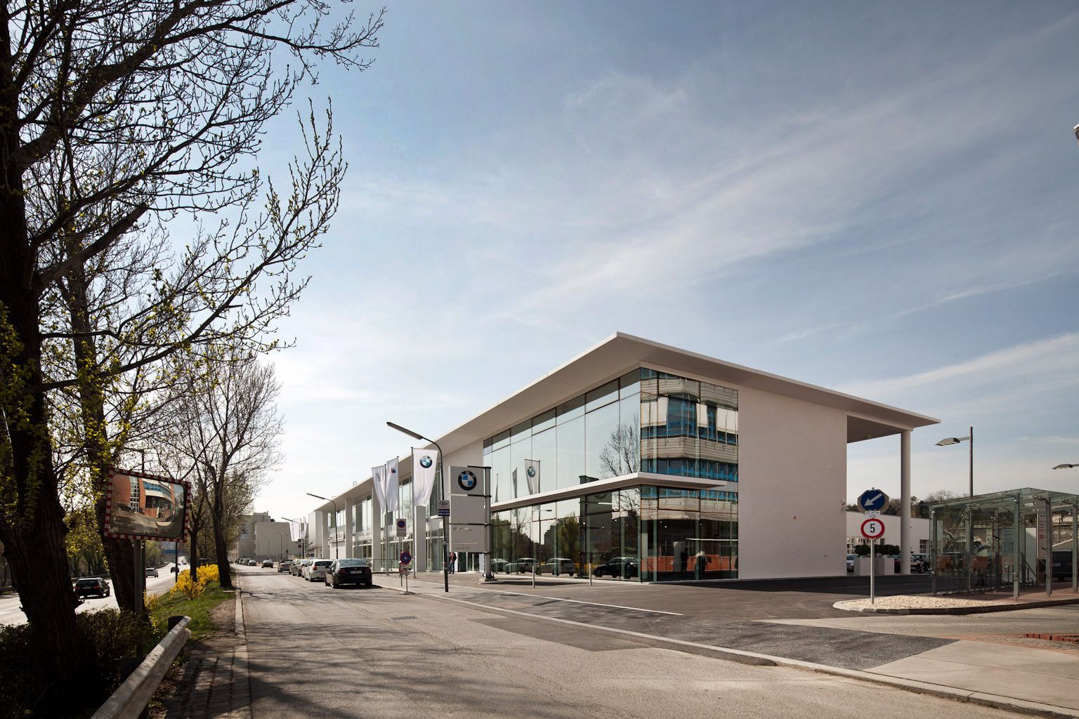 Seitenansicht der BMW Group Niederlassung Wien, bei der die große Fensterfront im Mittelpunkt des Bildes steht.