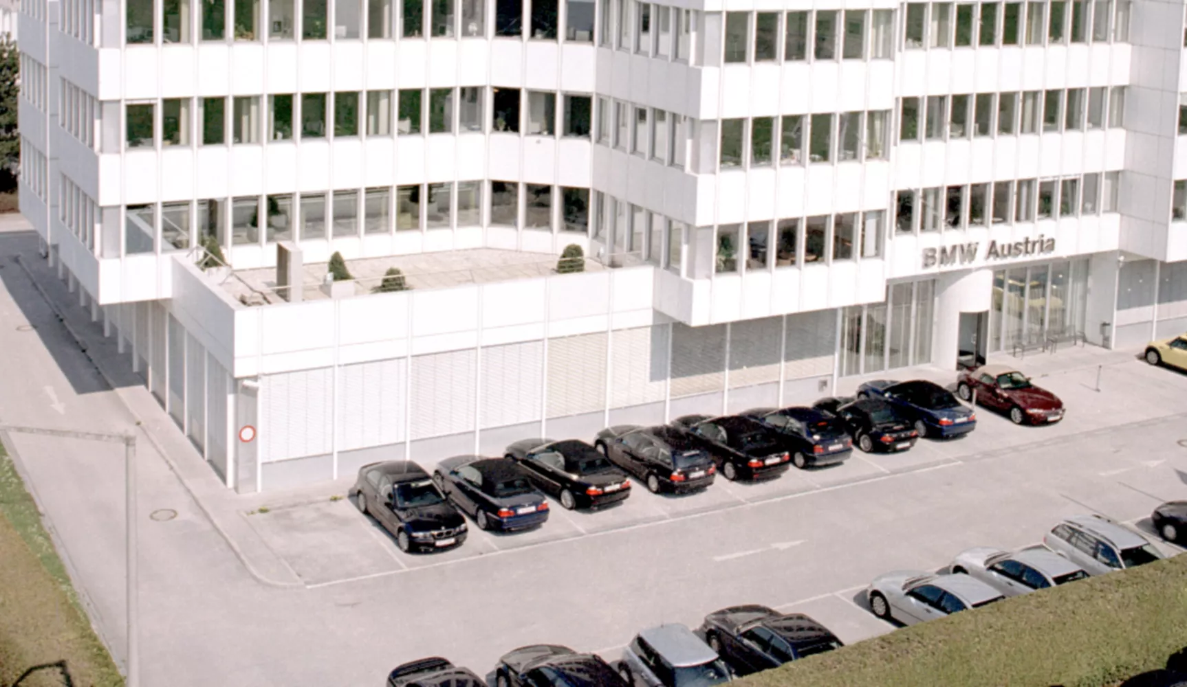 Ansicht der Vorderseite des BMW Group Standort Salzburg Campus Süd. Davor parken verschiedene Fahrzeuge.