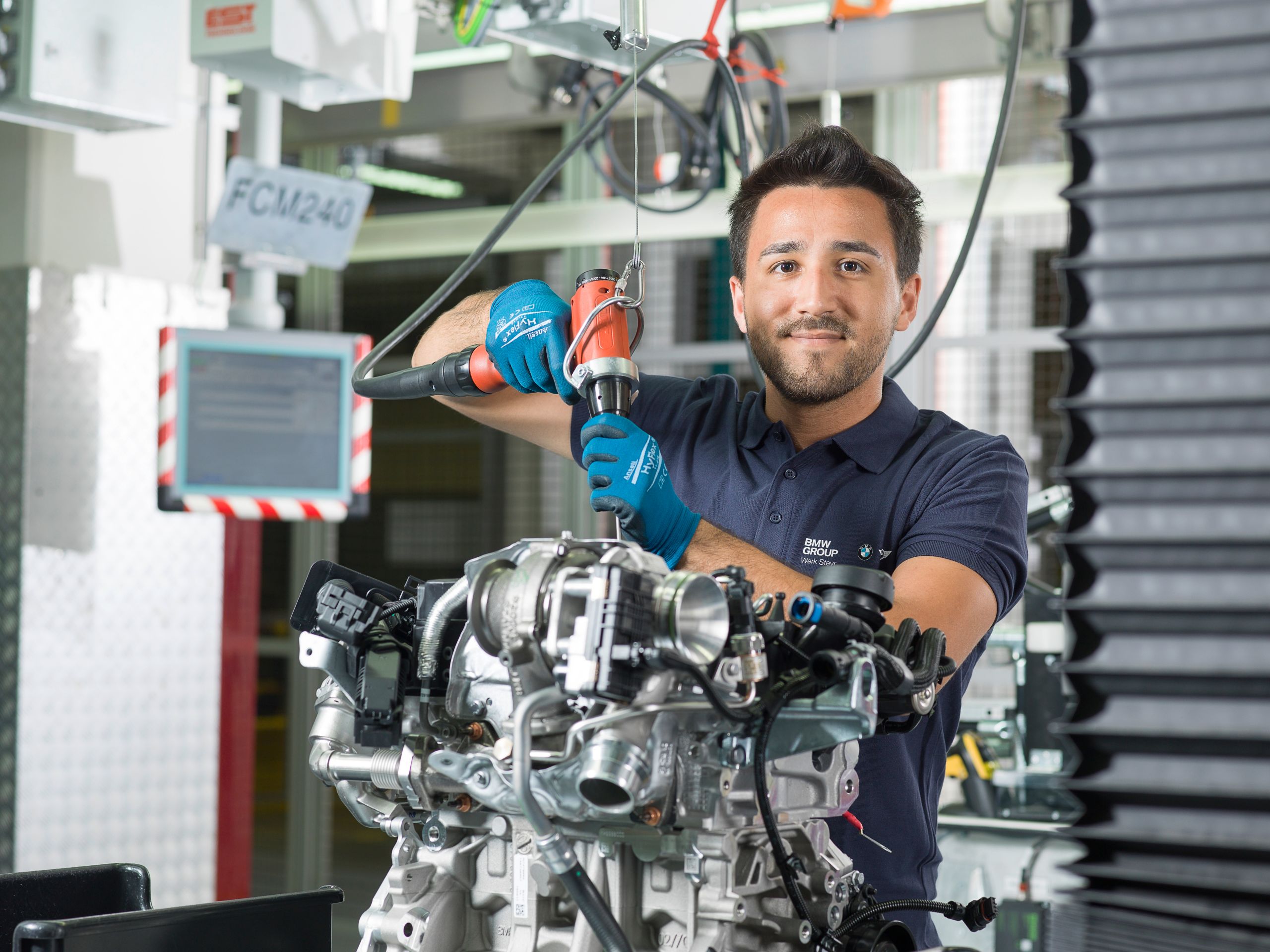 Ein Mitarbeiter des BMW Group Werk Steyr arbeitet gerade in einer Fertigungsstraße an einem Verbrennungsmotor der BMW Group.
