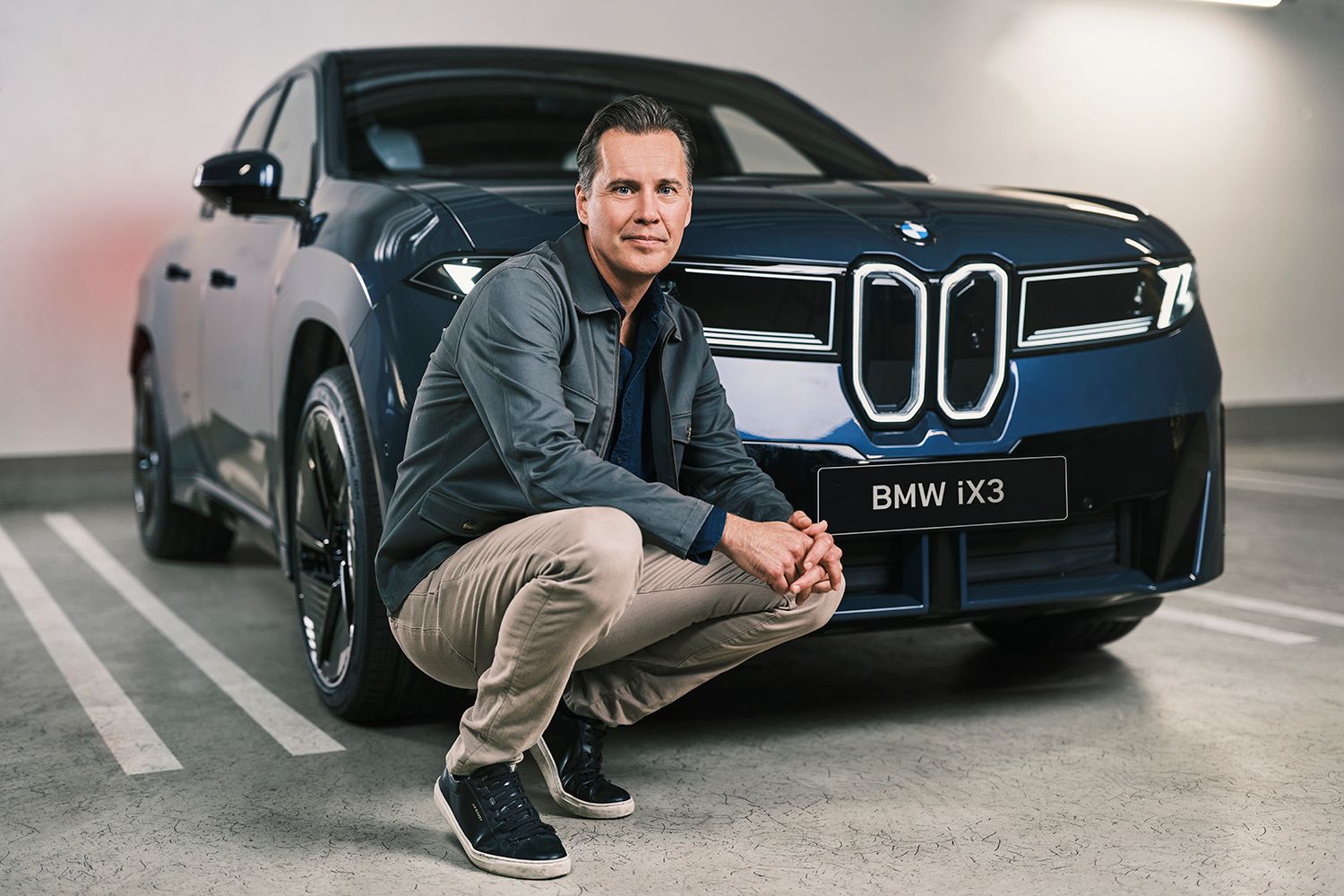 Carl Lindwall står framför en blå BMW iX3