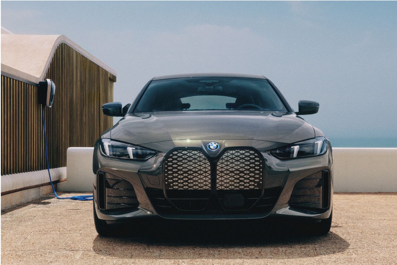 A BMW i4 charges outside with the BMW Wallbox home charger