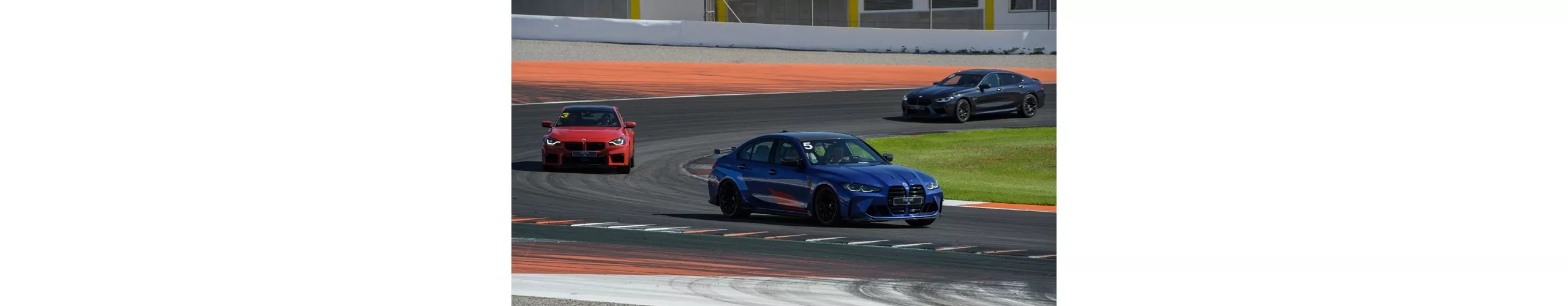 Três BMW a circular em alta velocidade numa pista, mostrando performance e dinamismo