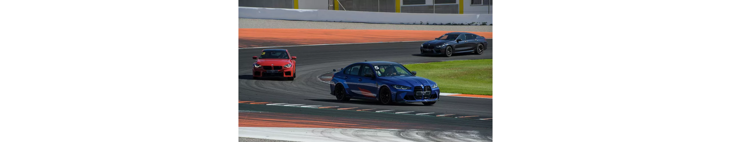 Três BMW a circular em alta velocidade numa pista, mostrando performance e dinamismo