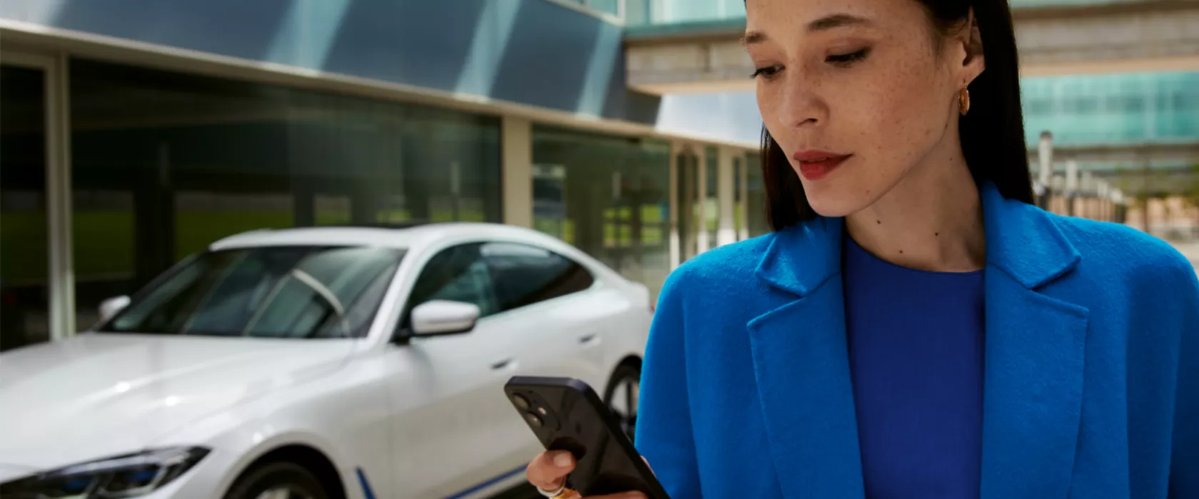 Femme devant la BWW i4 qui utilise son smartphone.