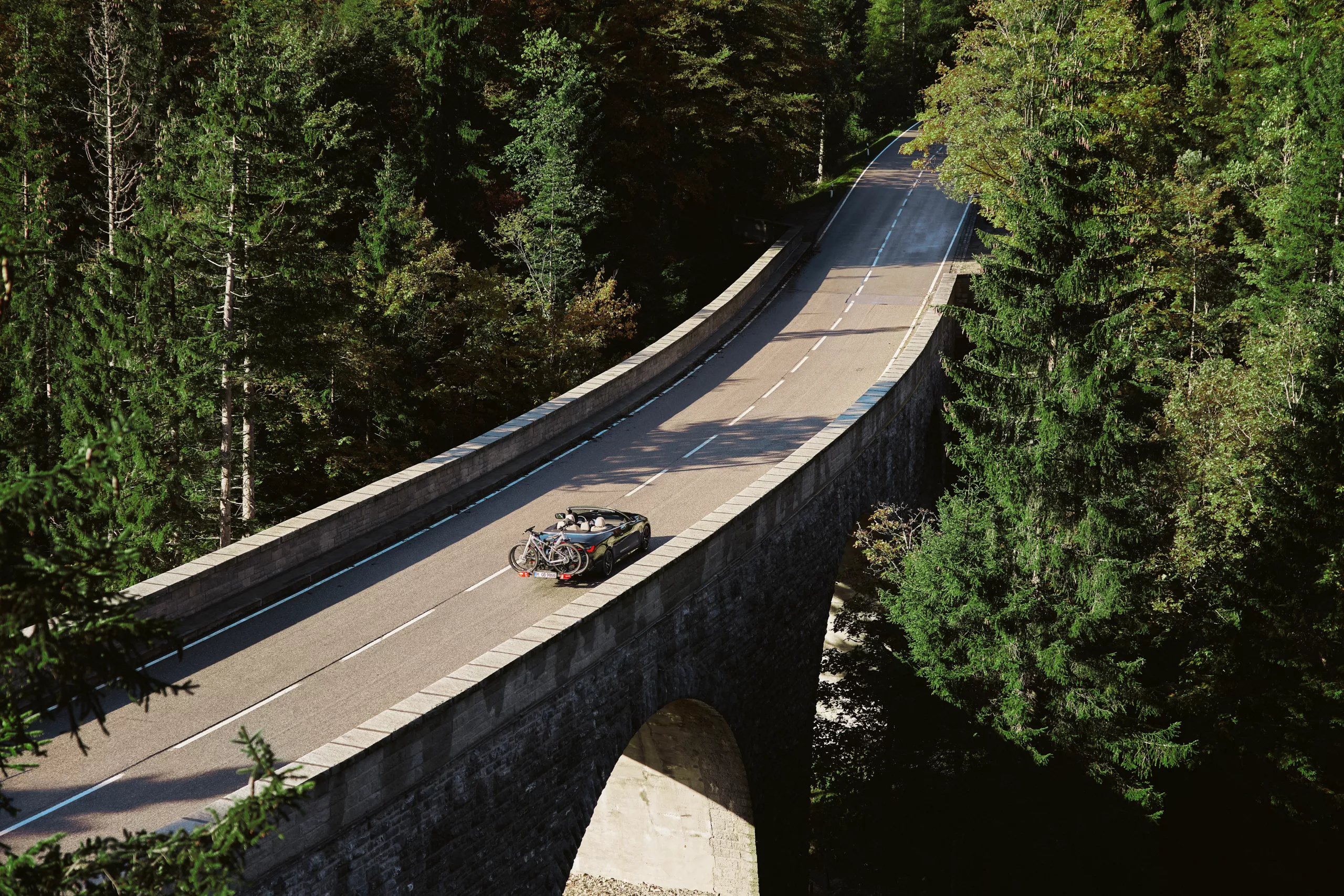  BMW 4 Series Convertible a circular na estrada no meio da natureza.