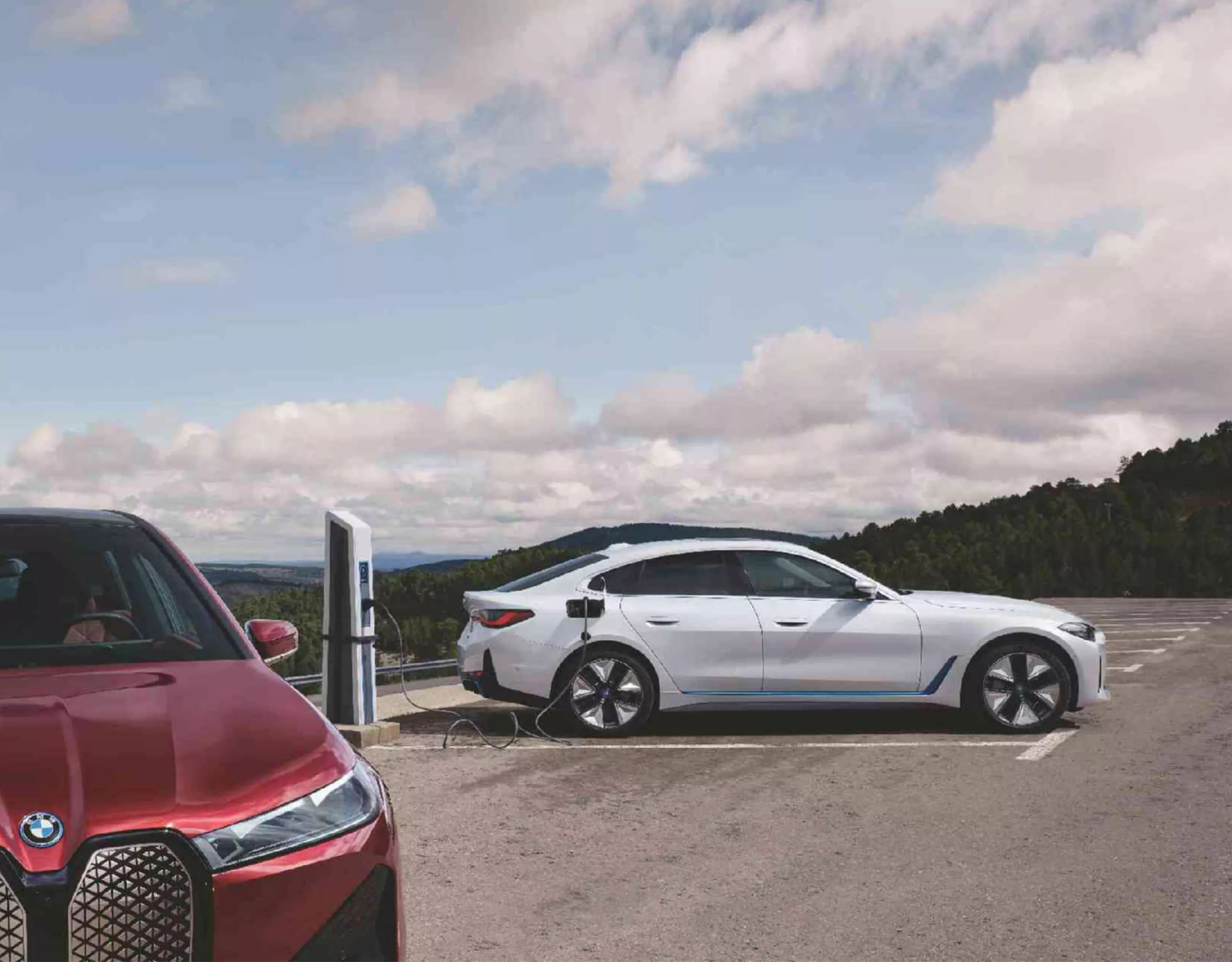 Deux véhicules électriques BMW en rouge et bleu sur une route surréaliste