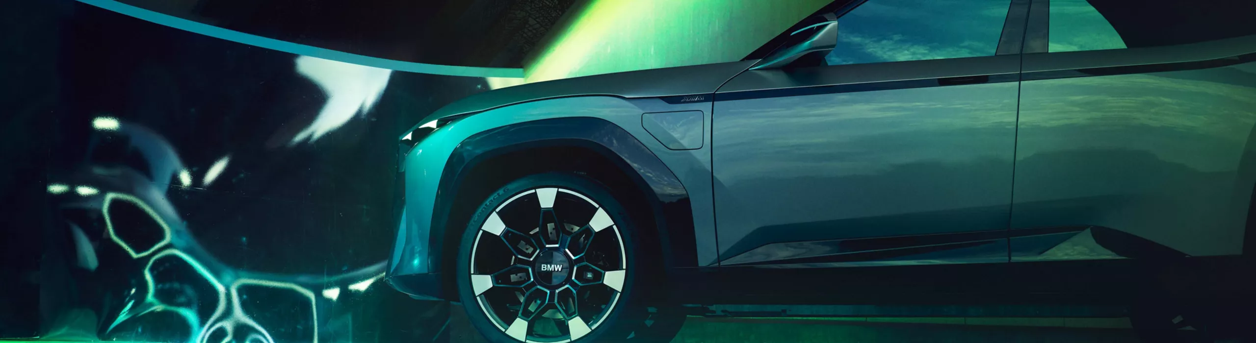Side view of a futuristic BMW electric SUV under neon green lighting in a modern urban setting