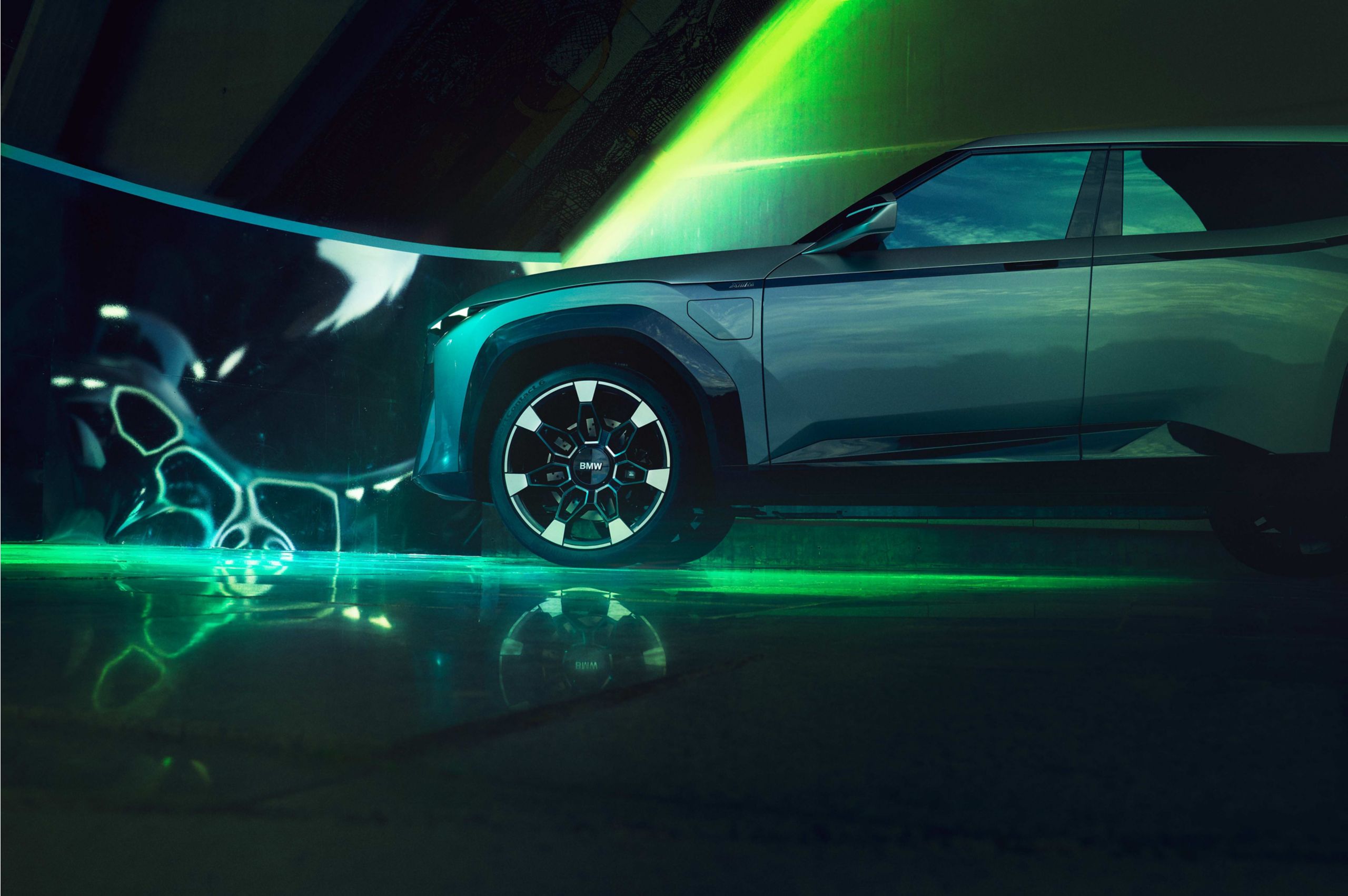 Side view of a futuristic BMW electric SUV under neon green lighting in a modern urban setting