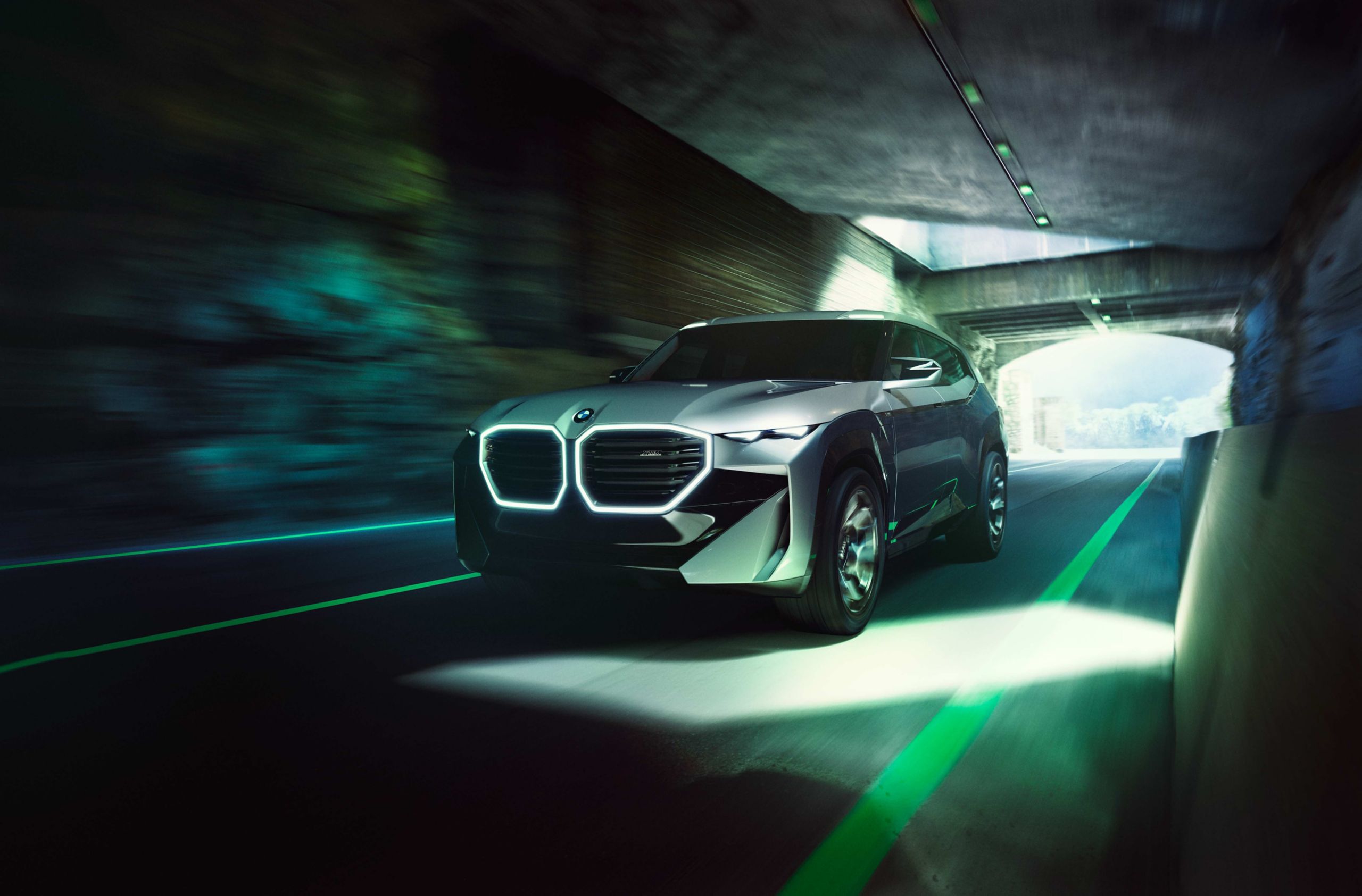 Futuristic BMW SUV with illuminated kidney grille driving through a tunnel at high speed