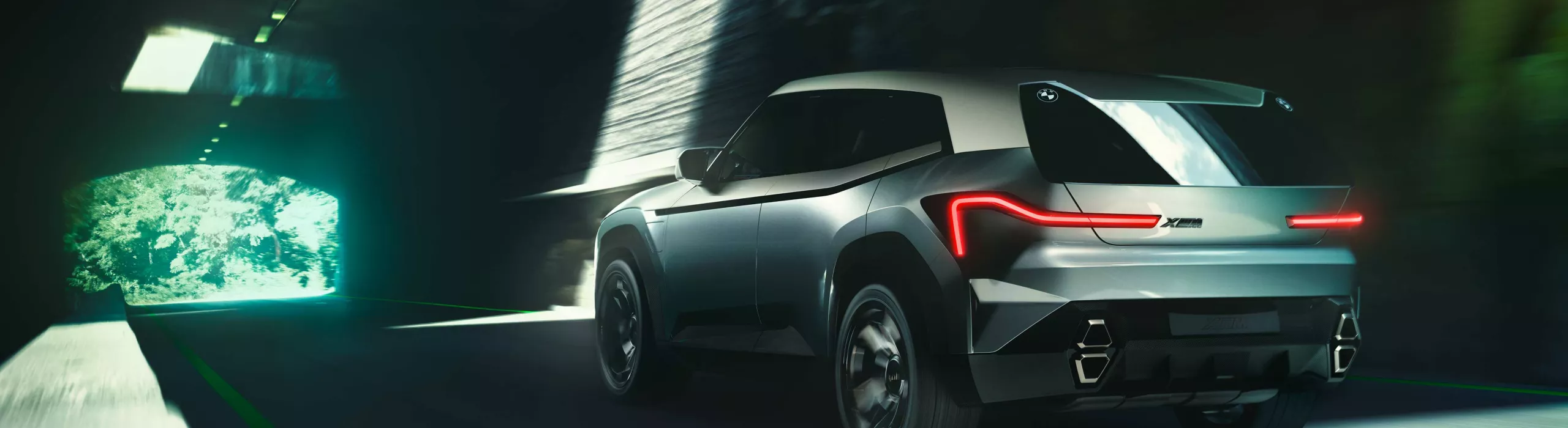Rear view of futuristic BMW concept SUV driving through a tunnel with sleek LED taillights and aerodynamic design