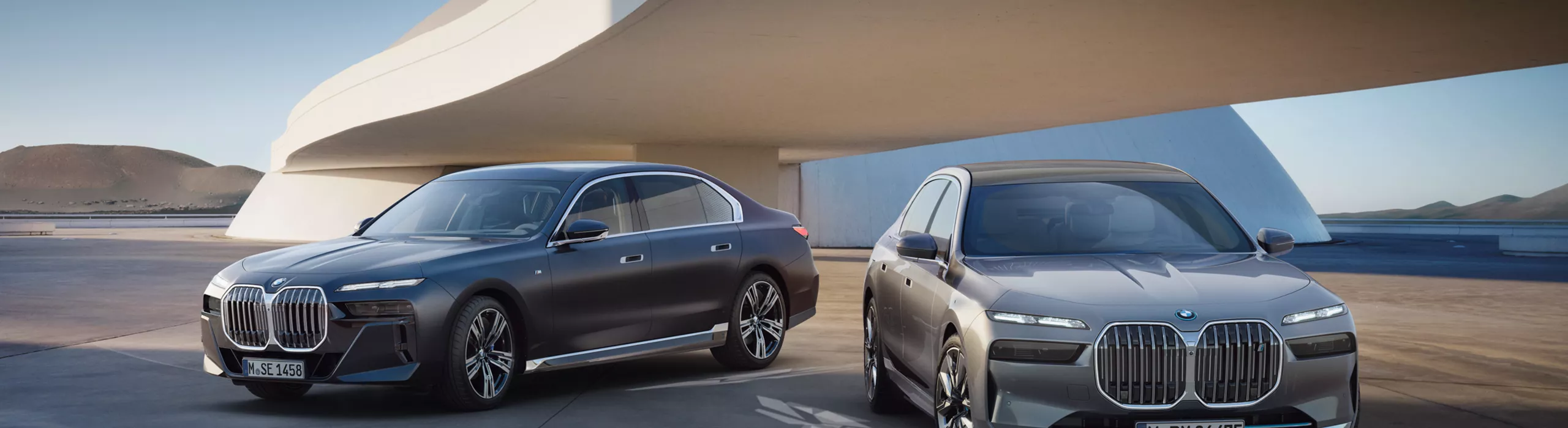 BMW i7 xDrive60 тау фонында айналмалы баспалдағы бар мұнараның алдындағы асфальт үстінде.