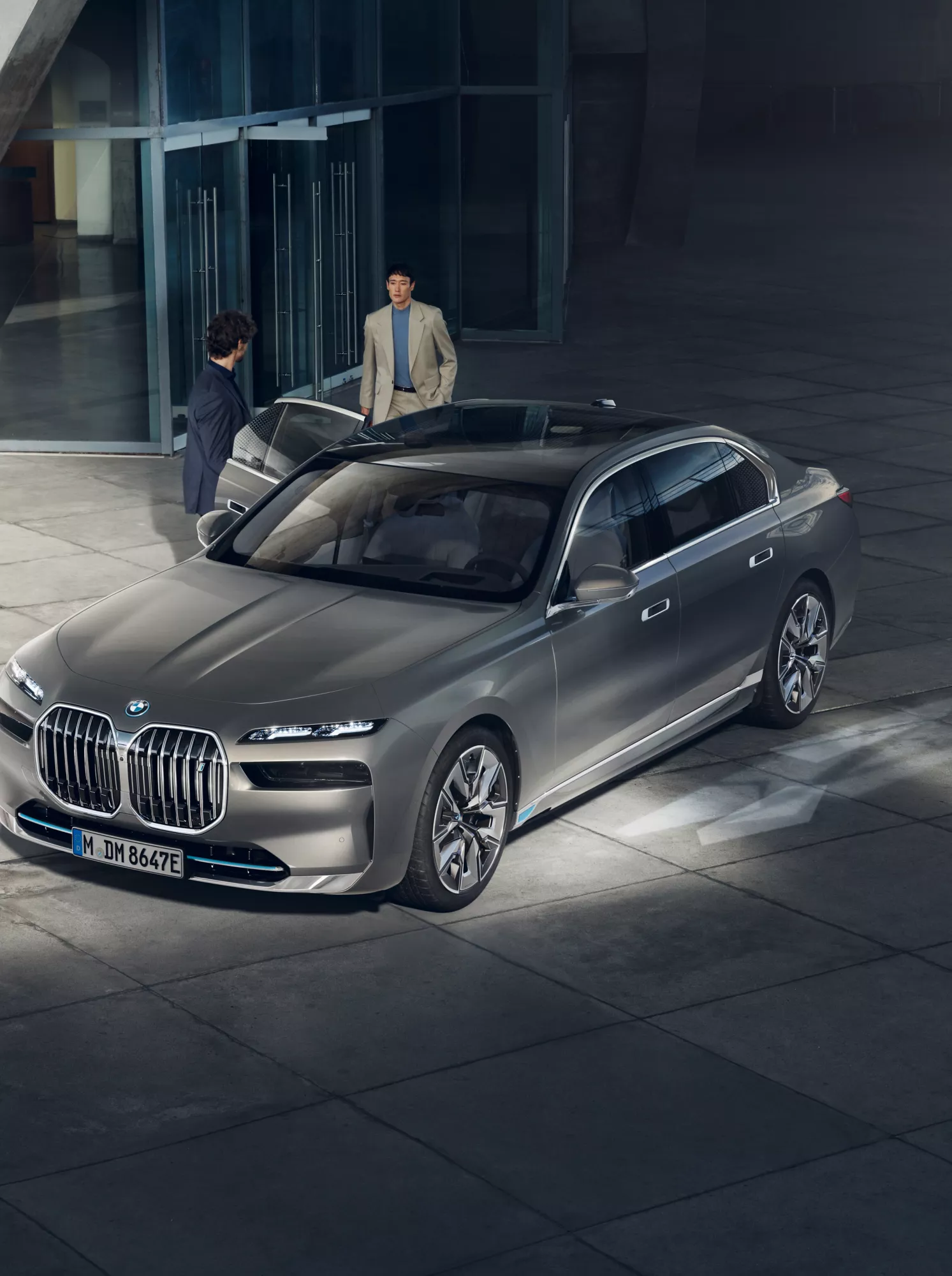 Vista de cima de duas pessoas junto a um veículo diplomático BMW em frente a um edifício