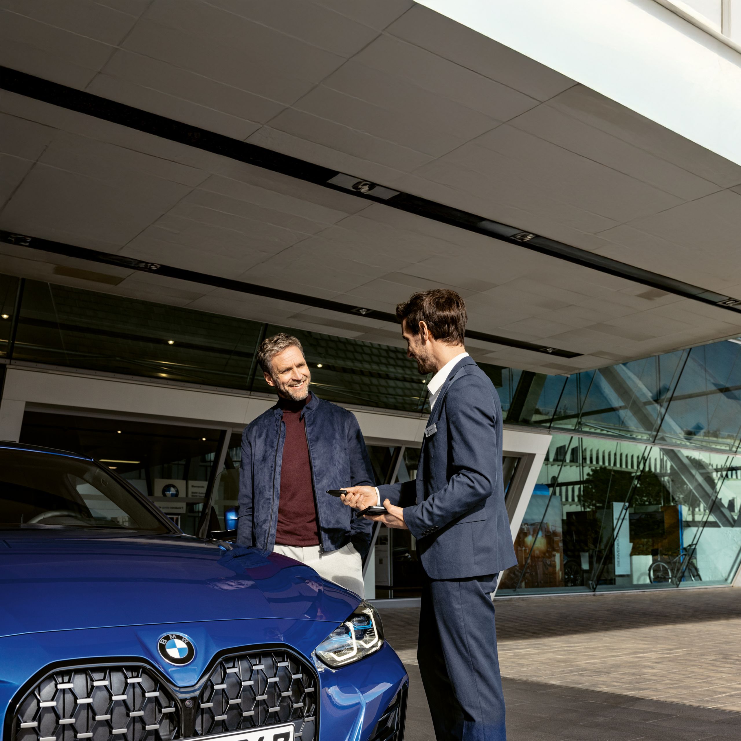  Un homme prend des notes dans un carnet avec sa BMW en arrière plan