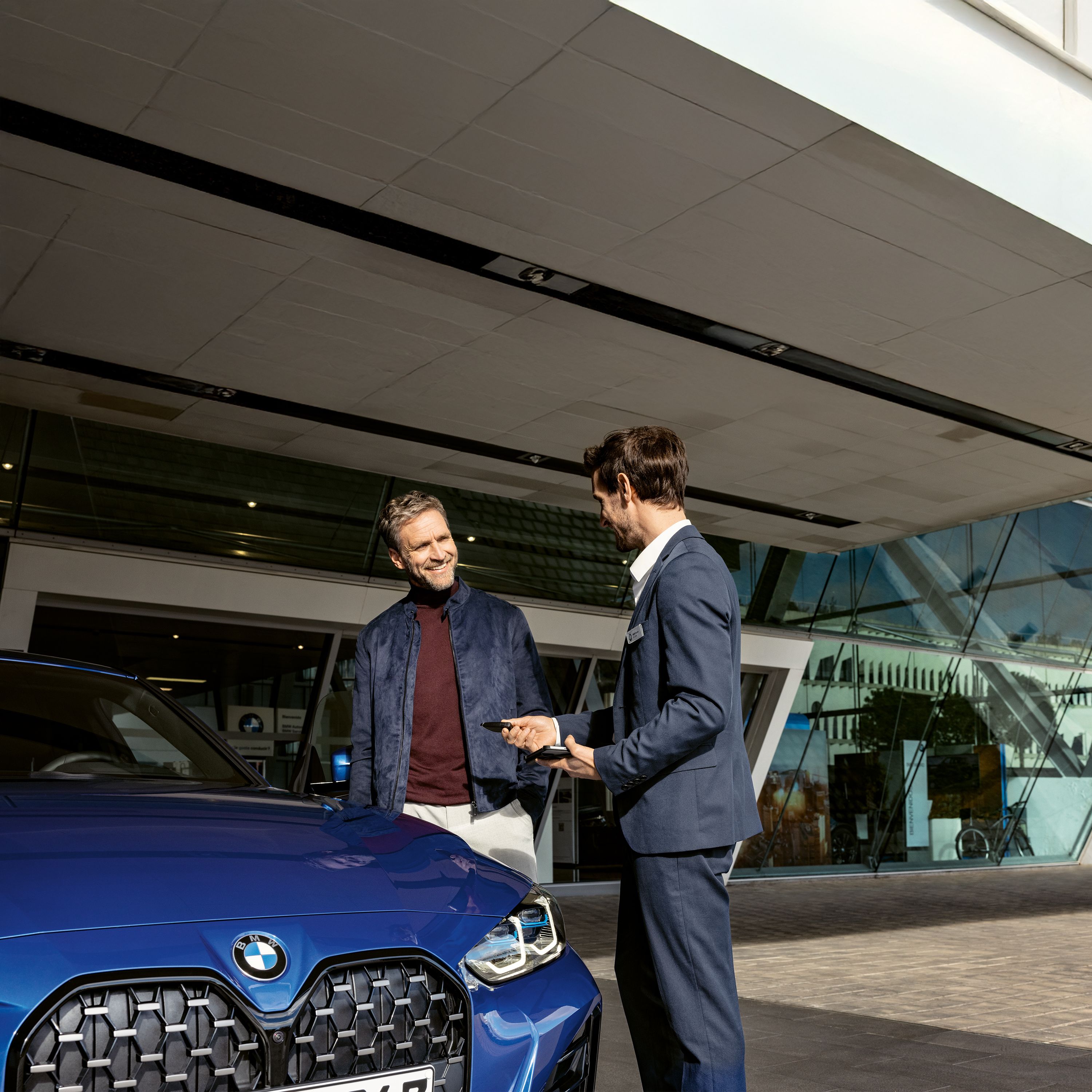  Un homme prend des notes dans un carnet avec sa BMW en arrière plan