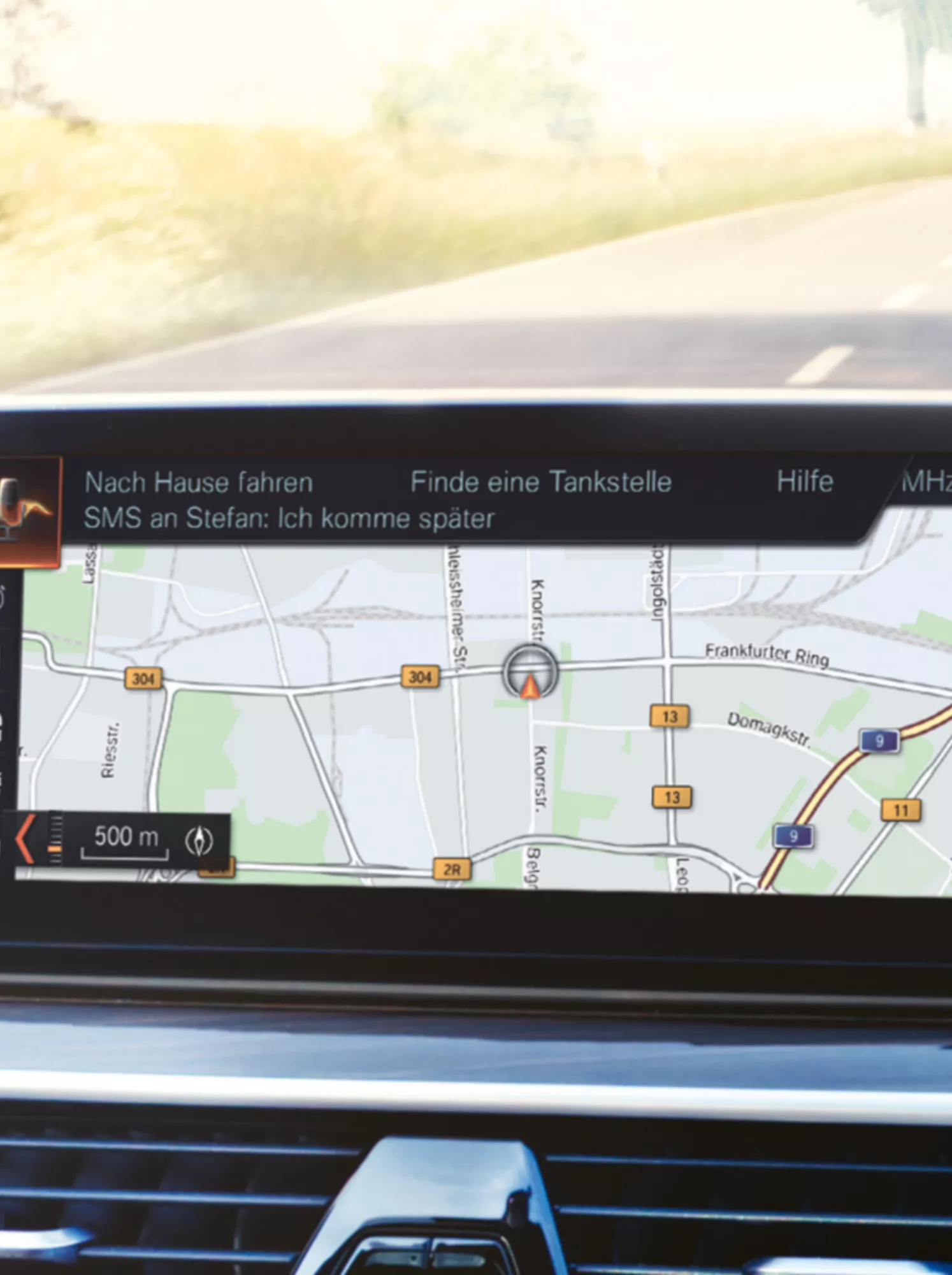 Navigationskarte auf BMW Infotainment Display während der Fahrt auf Landstraße mit sichtbarer Route und Menüanzeige