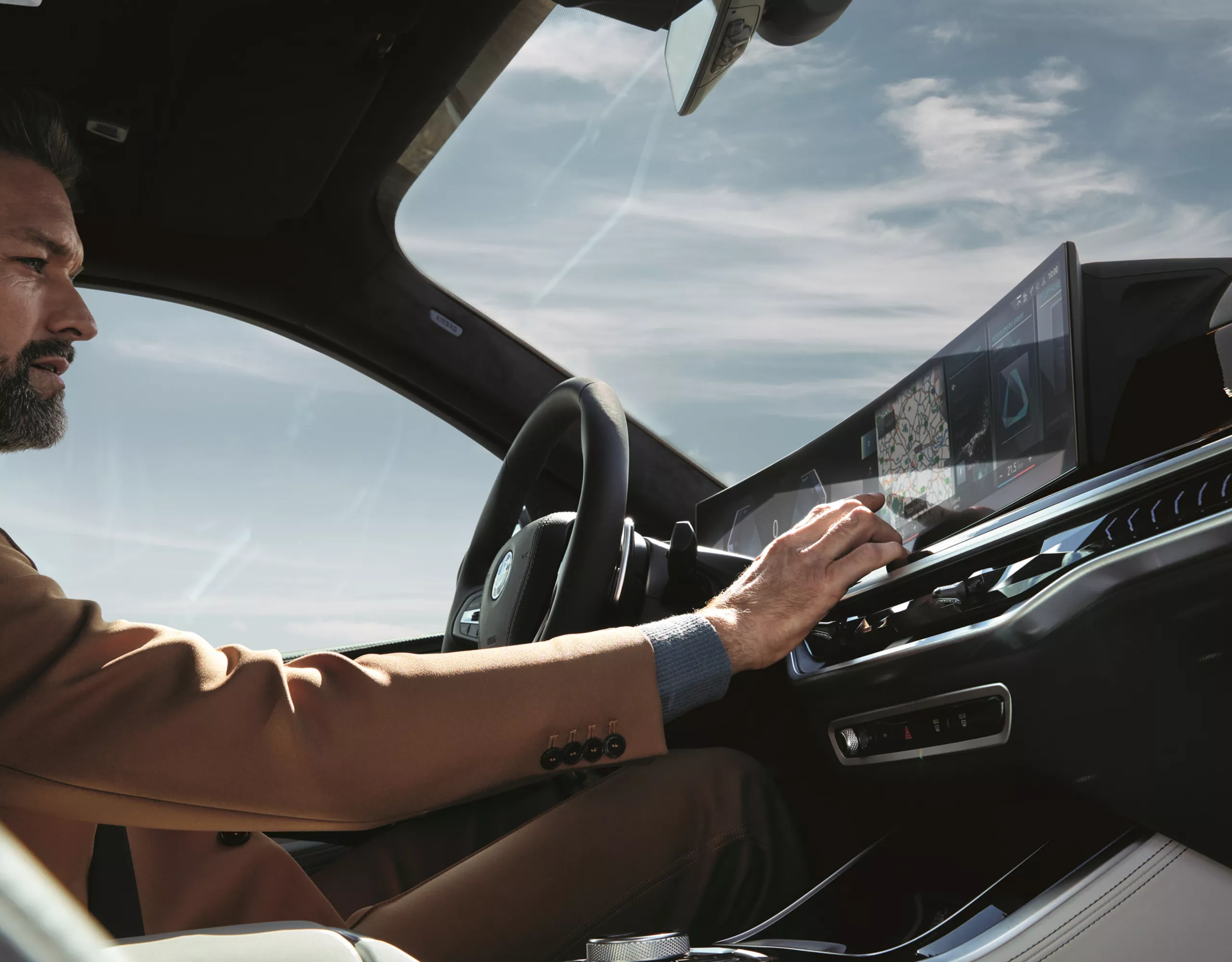 Un homme et une femme se tiennent devant une BMW et regardent ensemble une tablette. Un mur d'escalade se trouve derrière la BMW