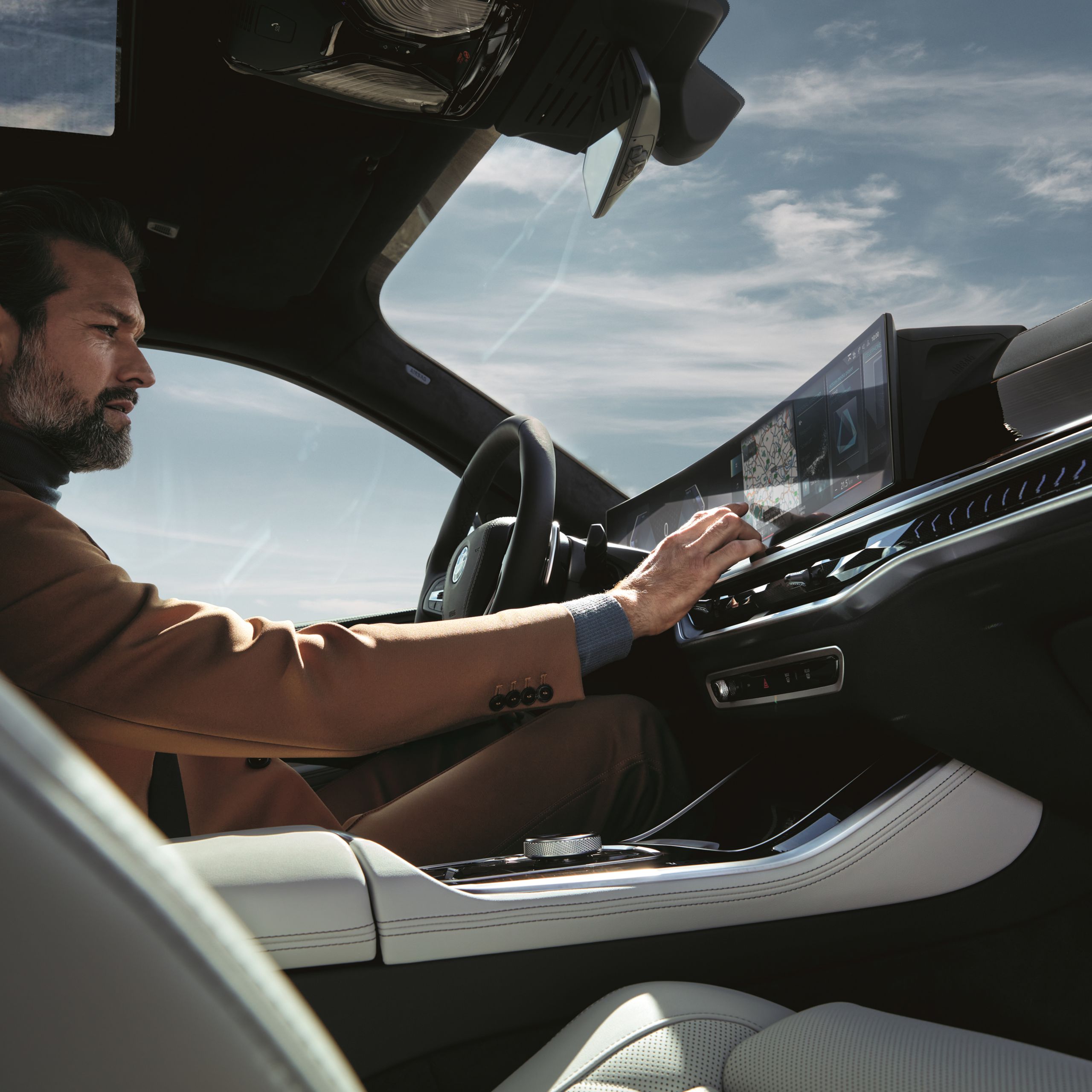 Man and woman stand in front of a BMW looking together at a tablet. A climbing wall can be seen behind the BMW