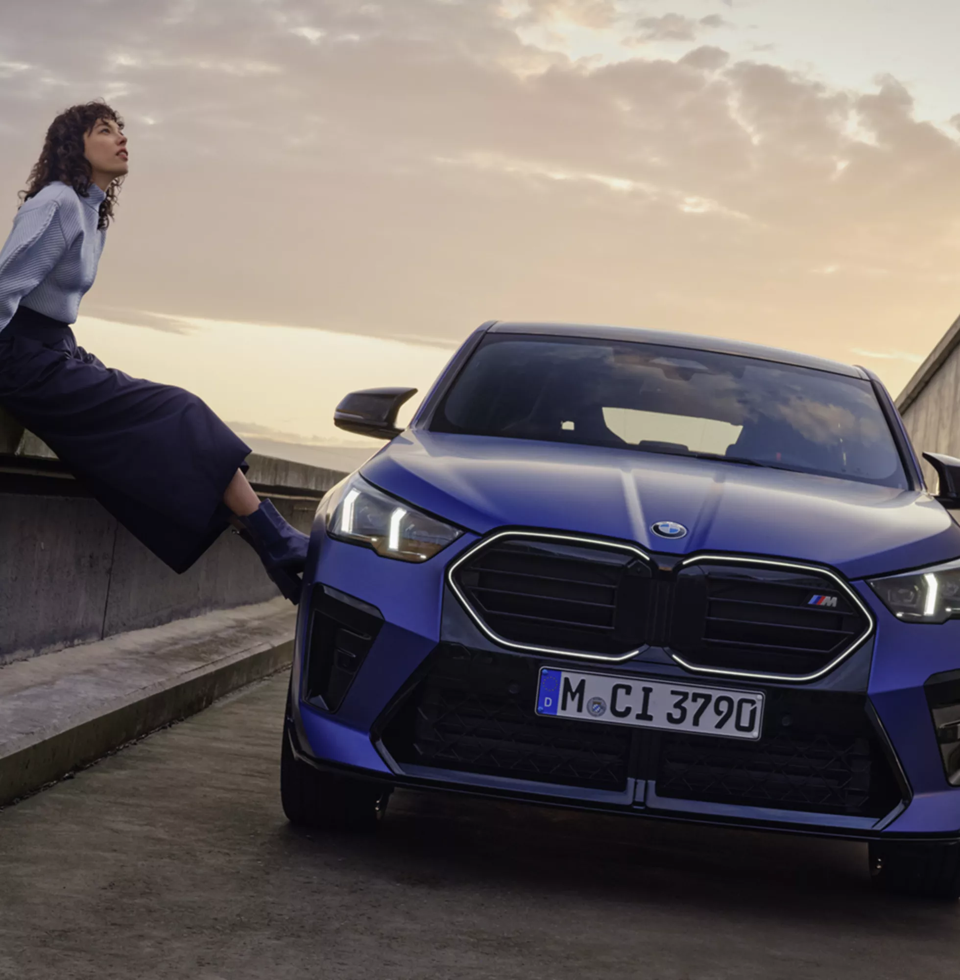 Woman with blue car at sunset