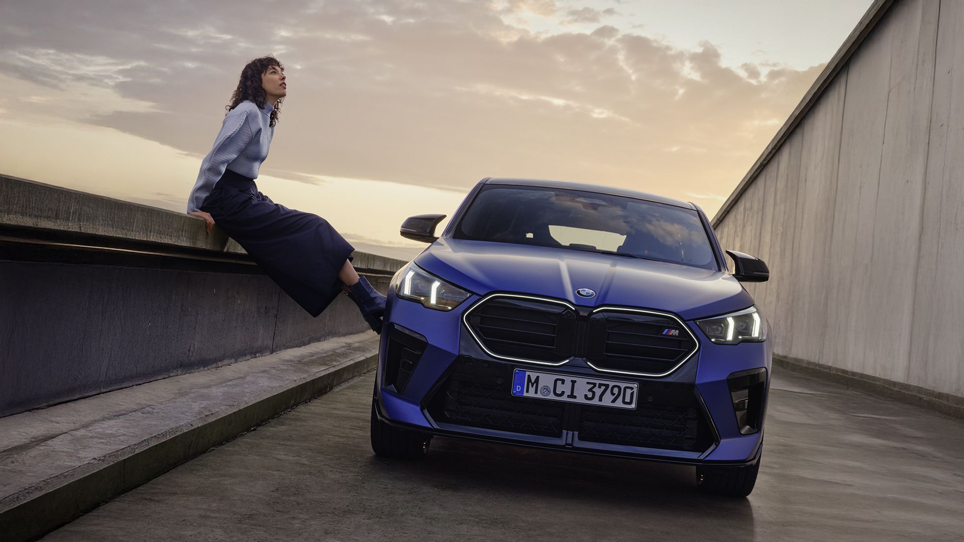 Woman with blue car at sunset