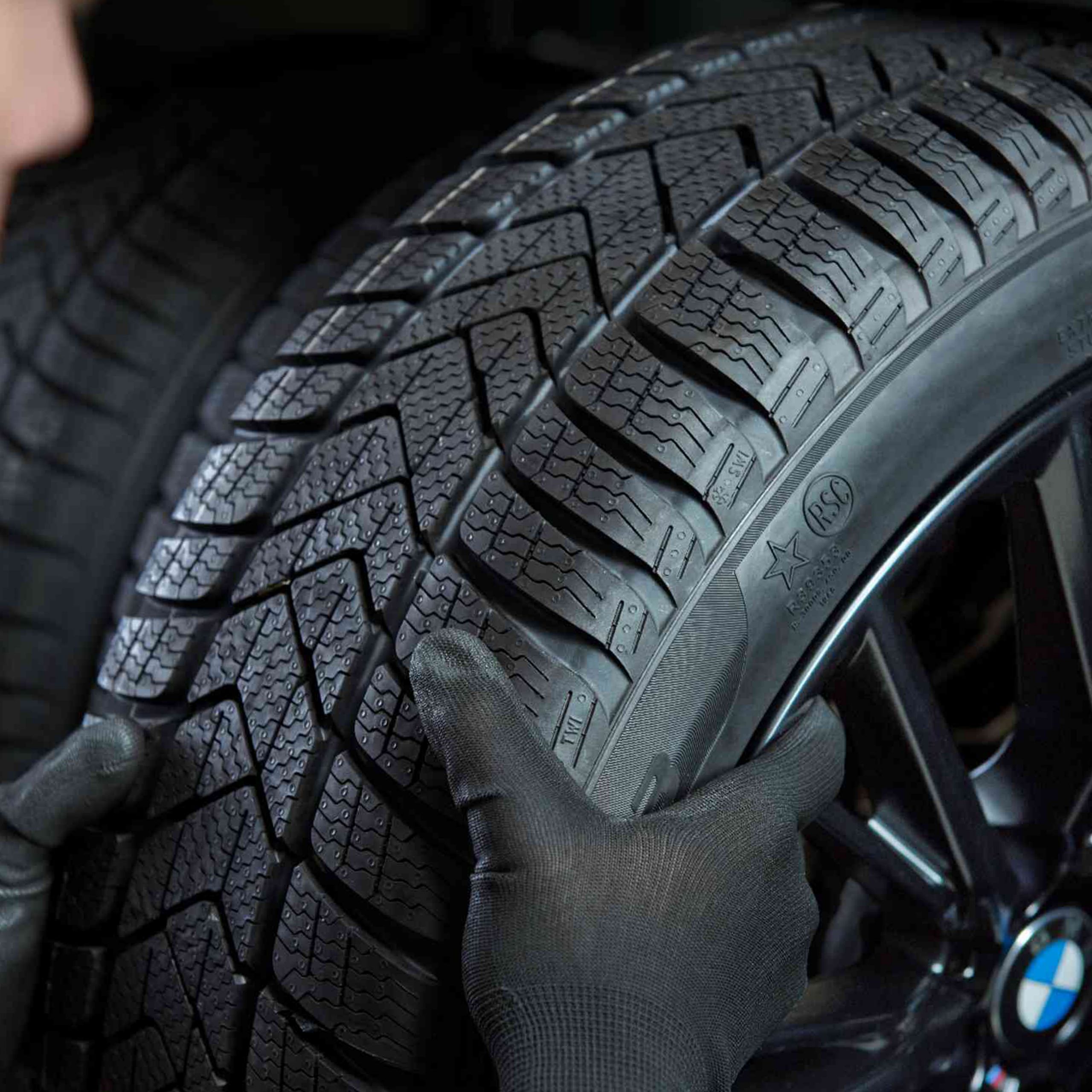 A group of people with backpacks and helmets approach a climbing wall. Next to them is a parked BMW