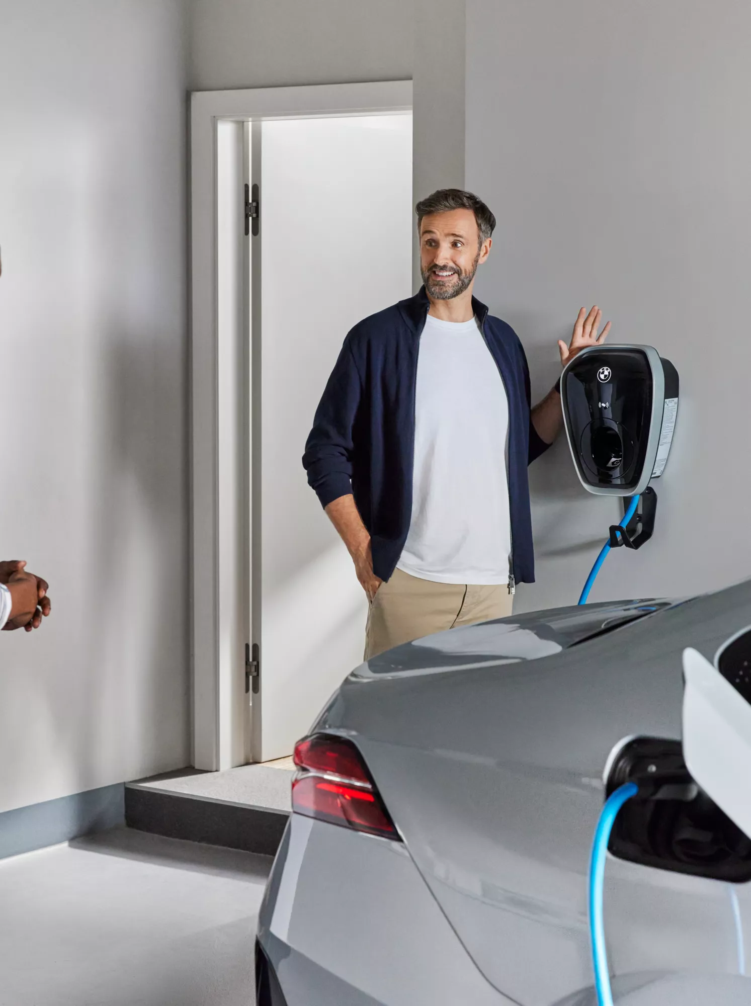 Dois homens ao lado de um BMW a carregar em casa com a BMW Wallbox Gen4.