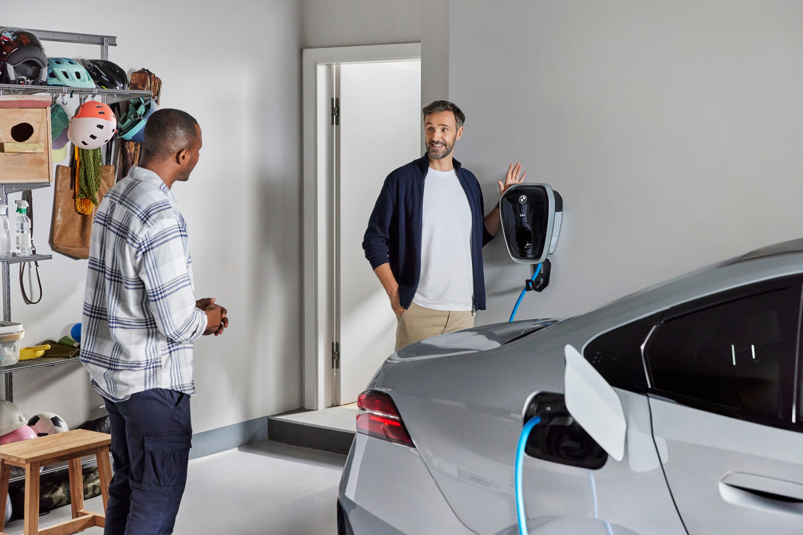 Dois homens ao lado de um BMW a carregar em casa com a BMW Wallbox Gen4.