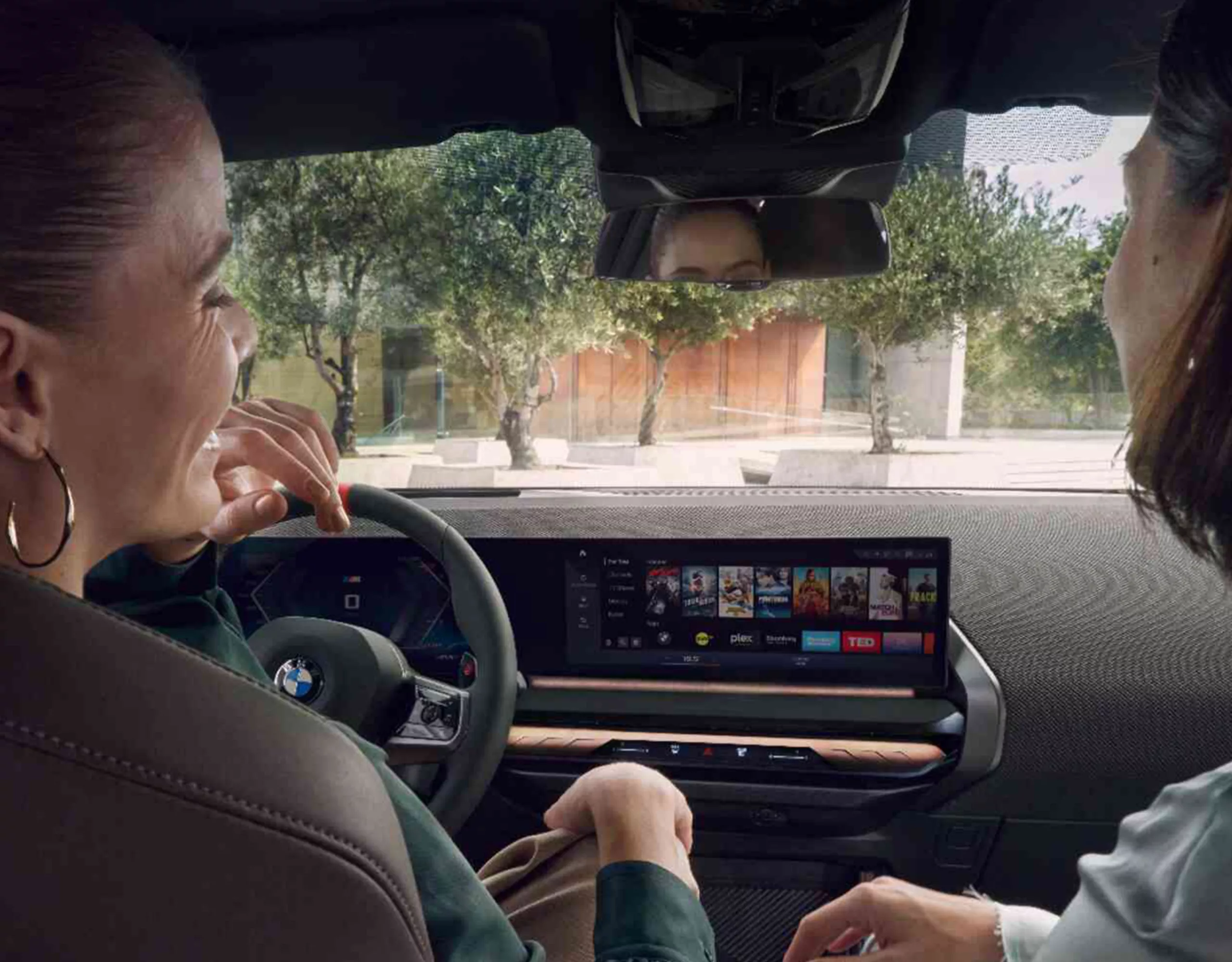 Un groupe de personnes avec des sacs à dos et des casques s’avance vers un mur d’escalade. Une BMW est garée à côté