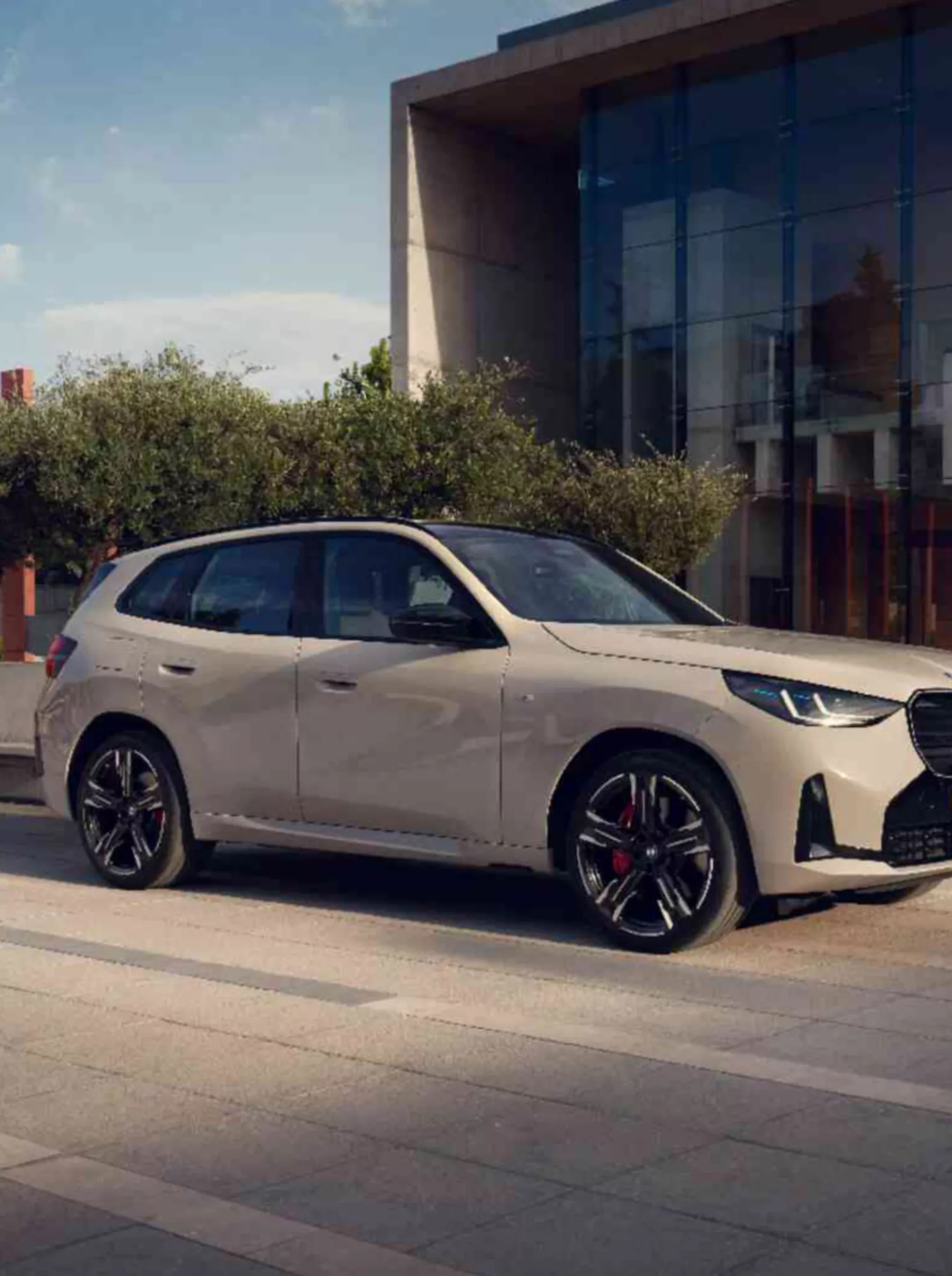 Una BMW X3 si trova davanti a un edificio moderno con una facciata in vetro
