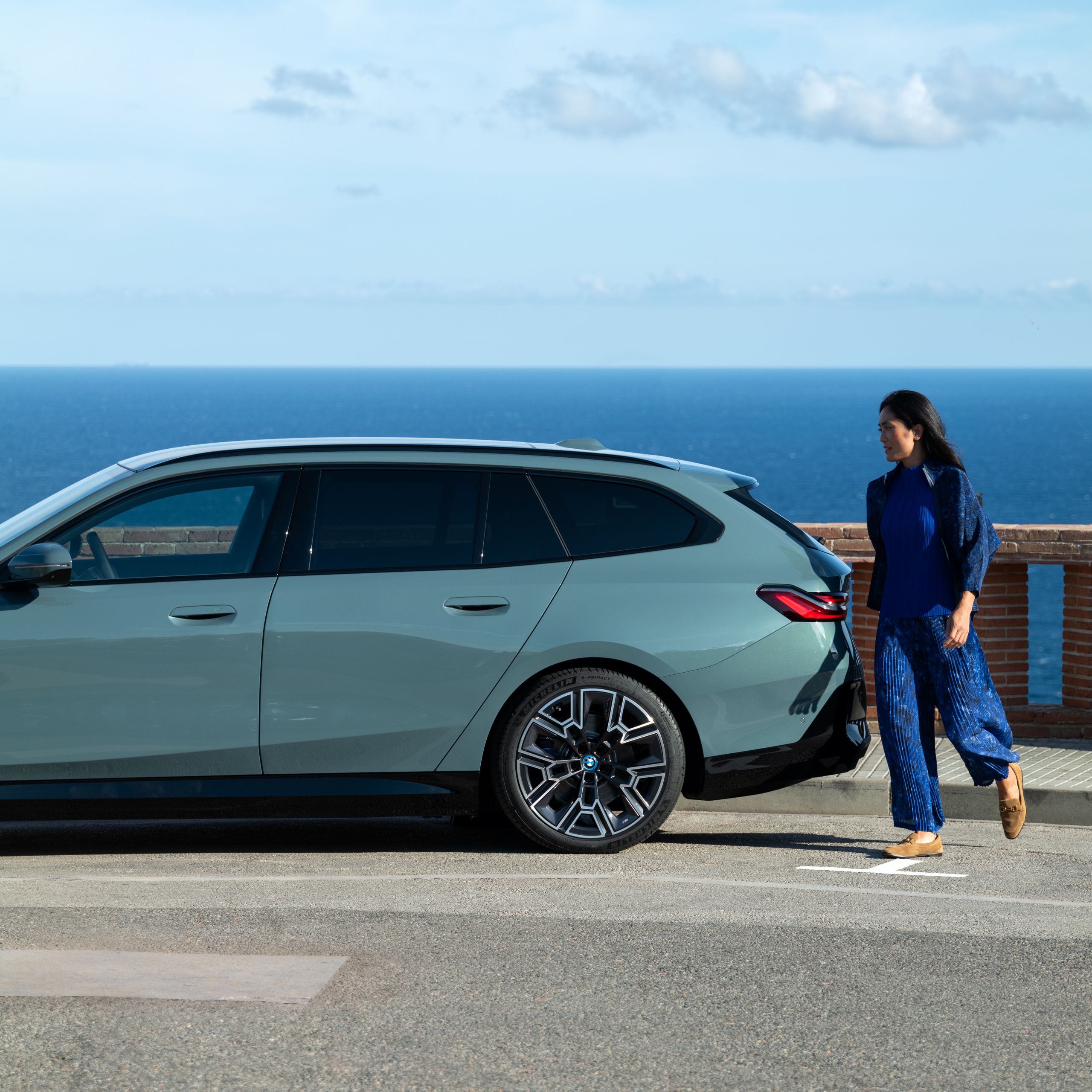 Eine Frau geht um das Hecks eines BMWs.