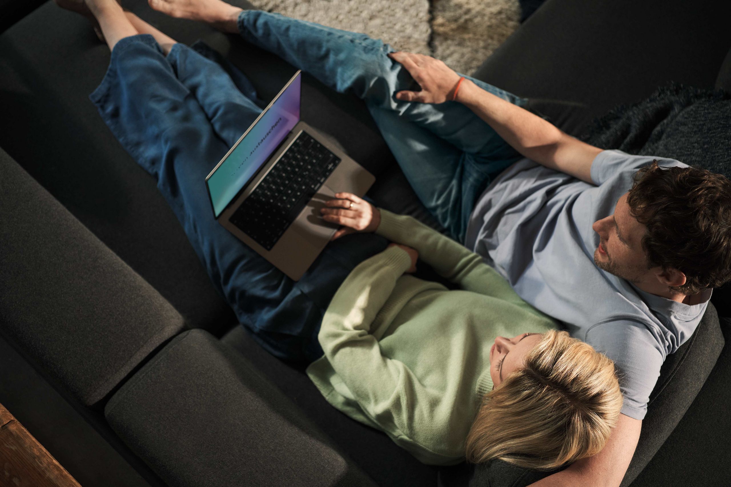 Girlfriend and boyfriend looking at laptop on couch. 