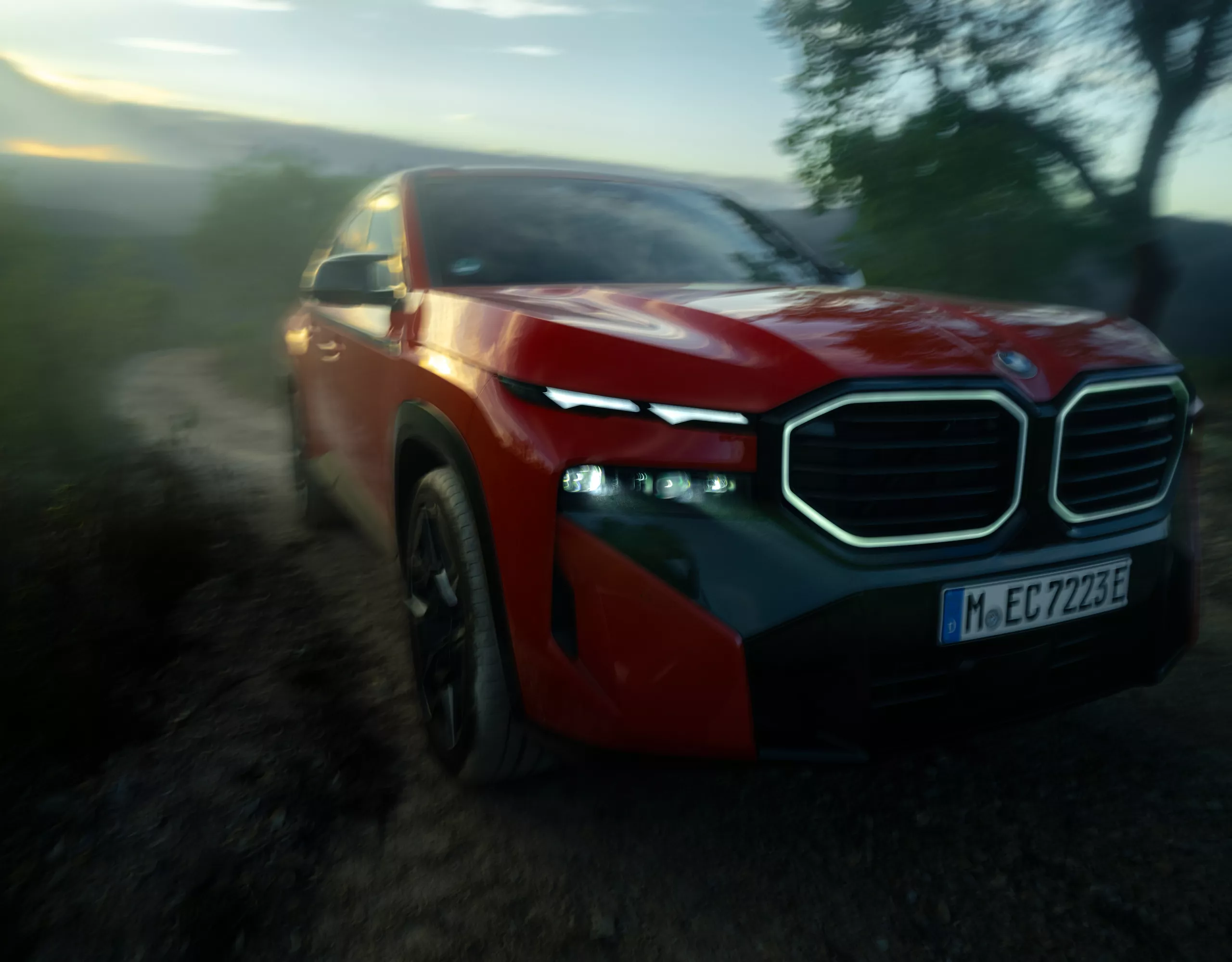 Ein roter sportlicher BMW fährt über eine Schotterstraße in einer grün bewachsenen Landschaft. 