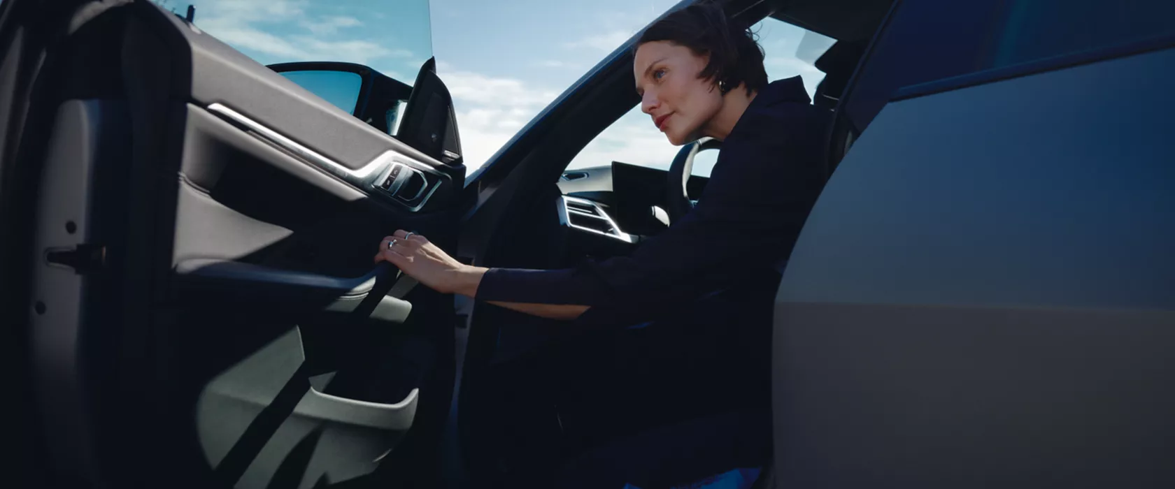 Eine Frau öffnet die Tür ihres BMWs.