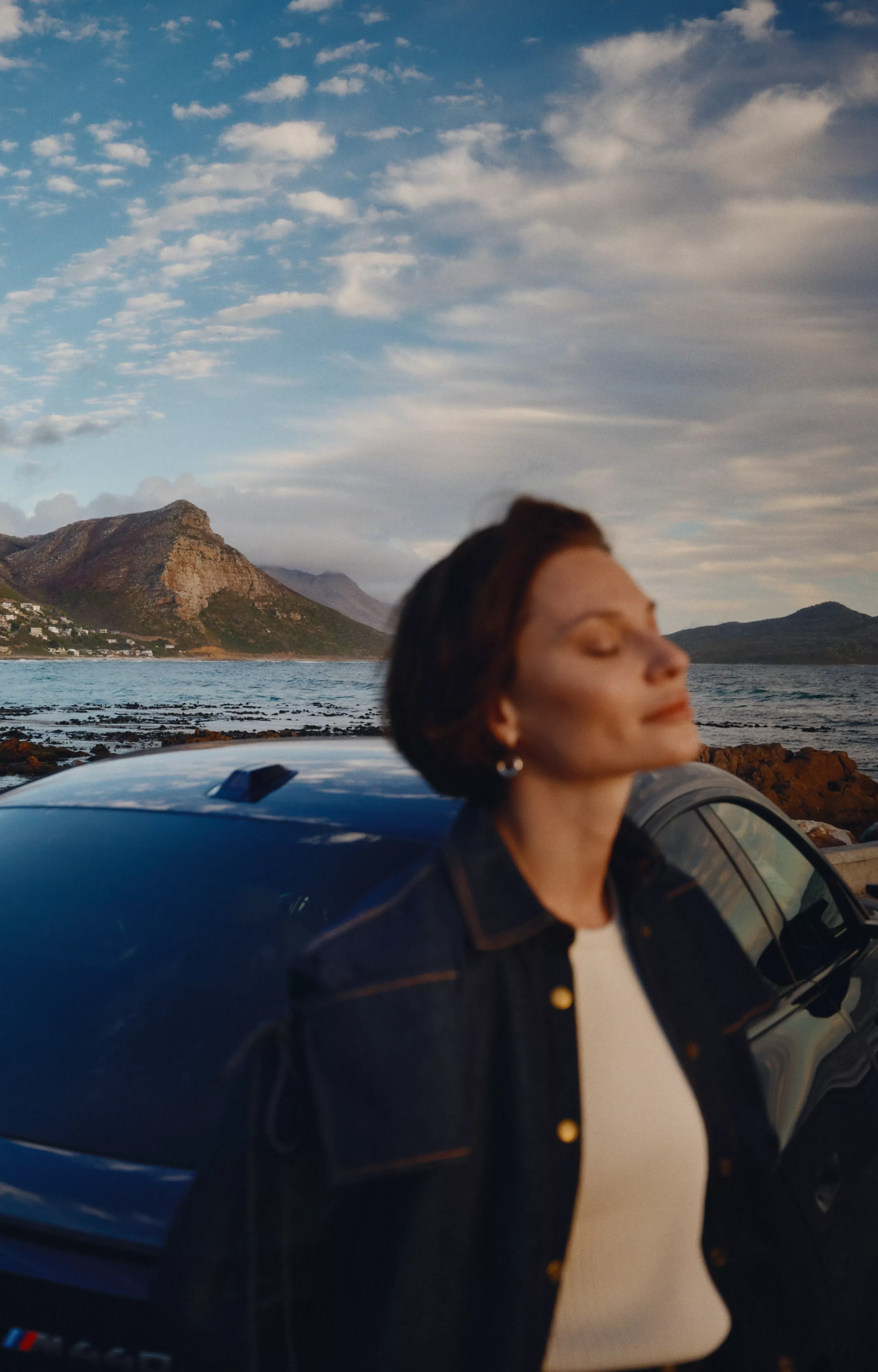 Person steht neben einem BMW mit Landschaft im Hintergrund.