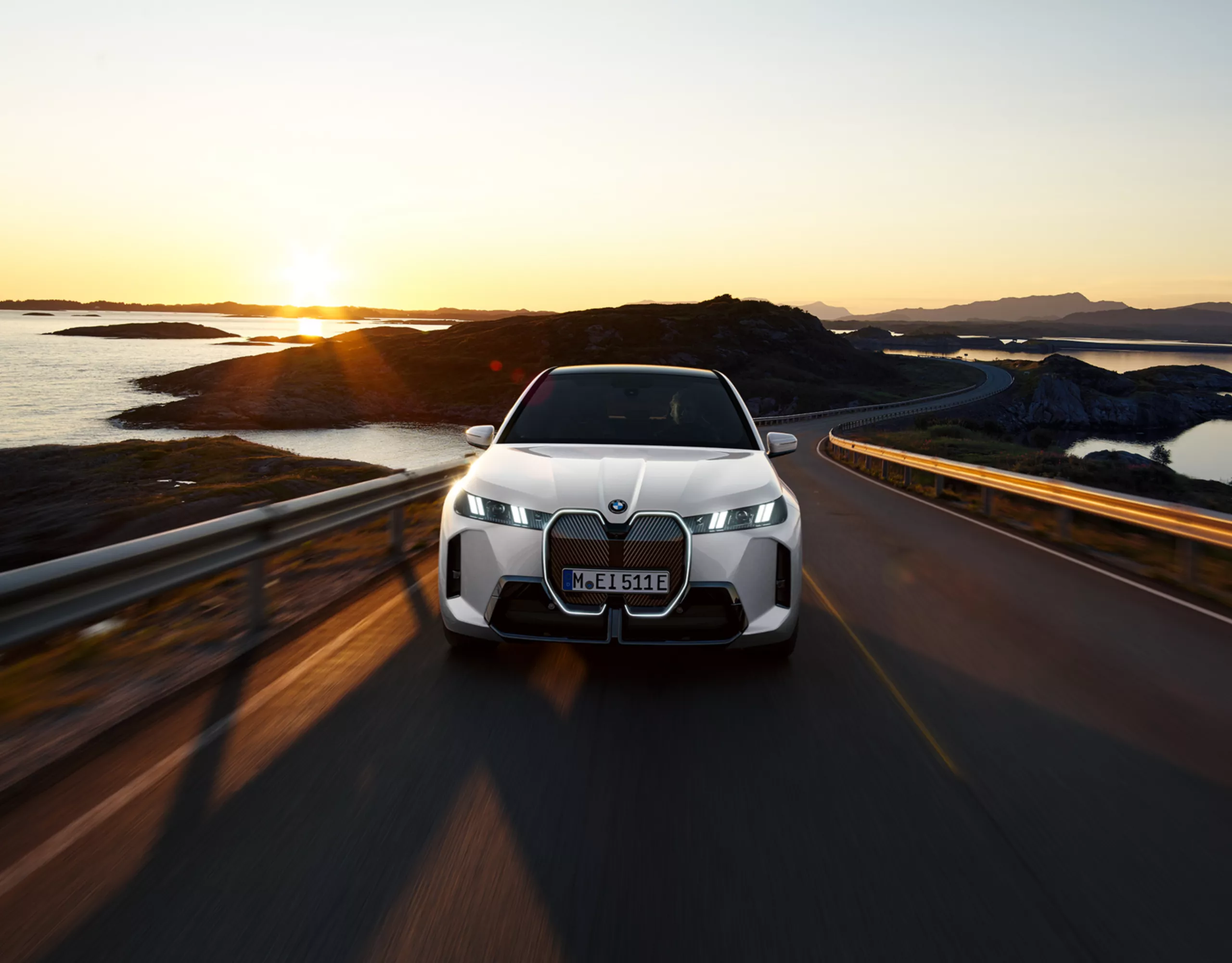 Man and woman stand in front of a BMW looking together at a tablet. A climbing wall can be seen behind the BMW