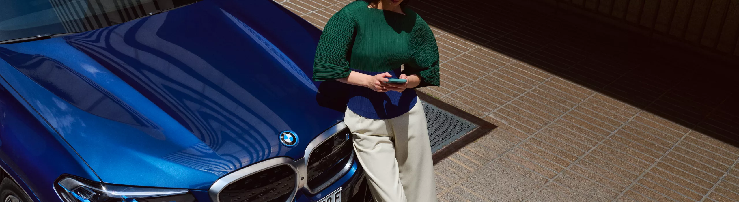 Mulher fazendo login no BMW Portal, junto de um BMW iX