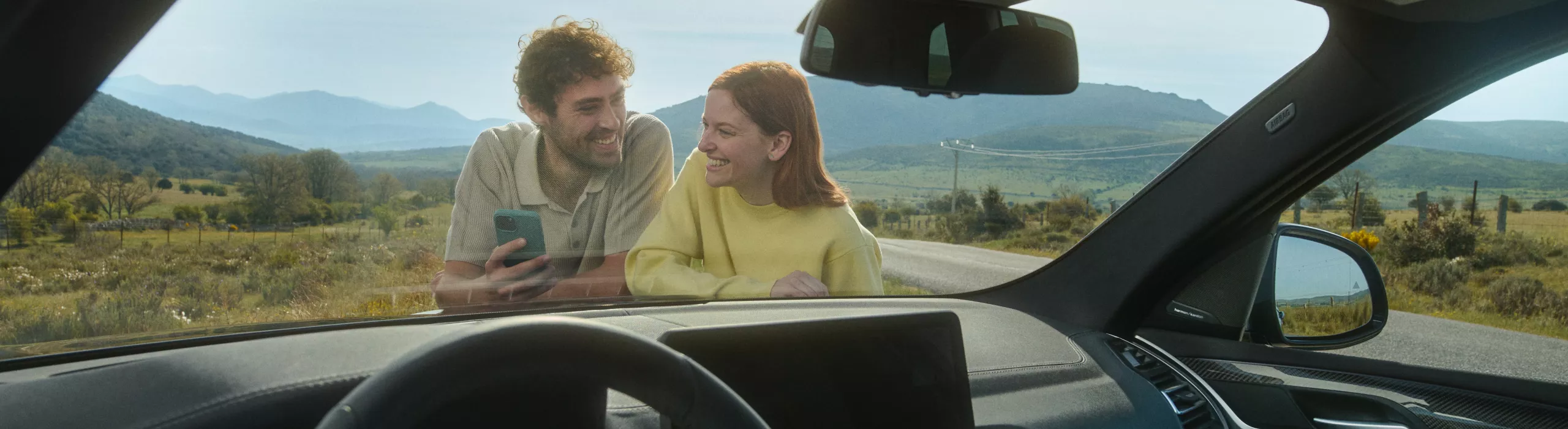 A fully electric BMW is plugged in to a charging station at the side of the road