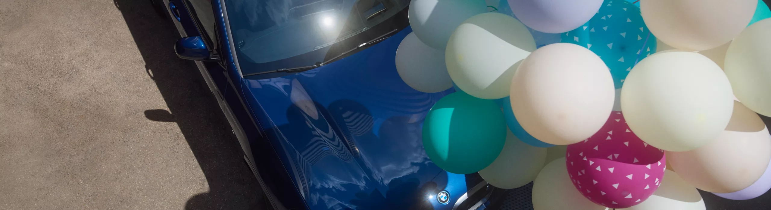Pärchen steht vor BMW iX3 auf einer Plattform in den Bergen