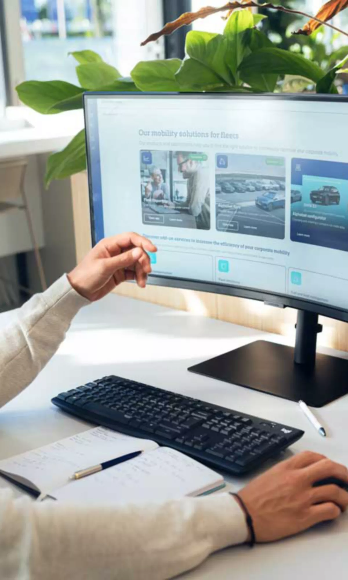 En person arbetar vid ett skrivbord med en dator i en modern kontorsmiljö.
